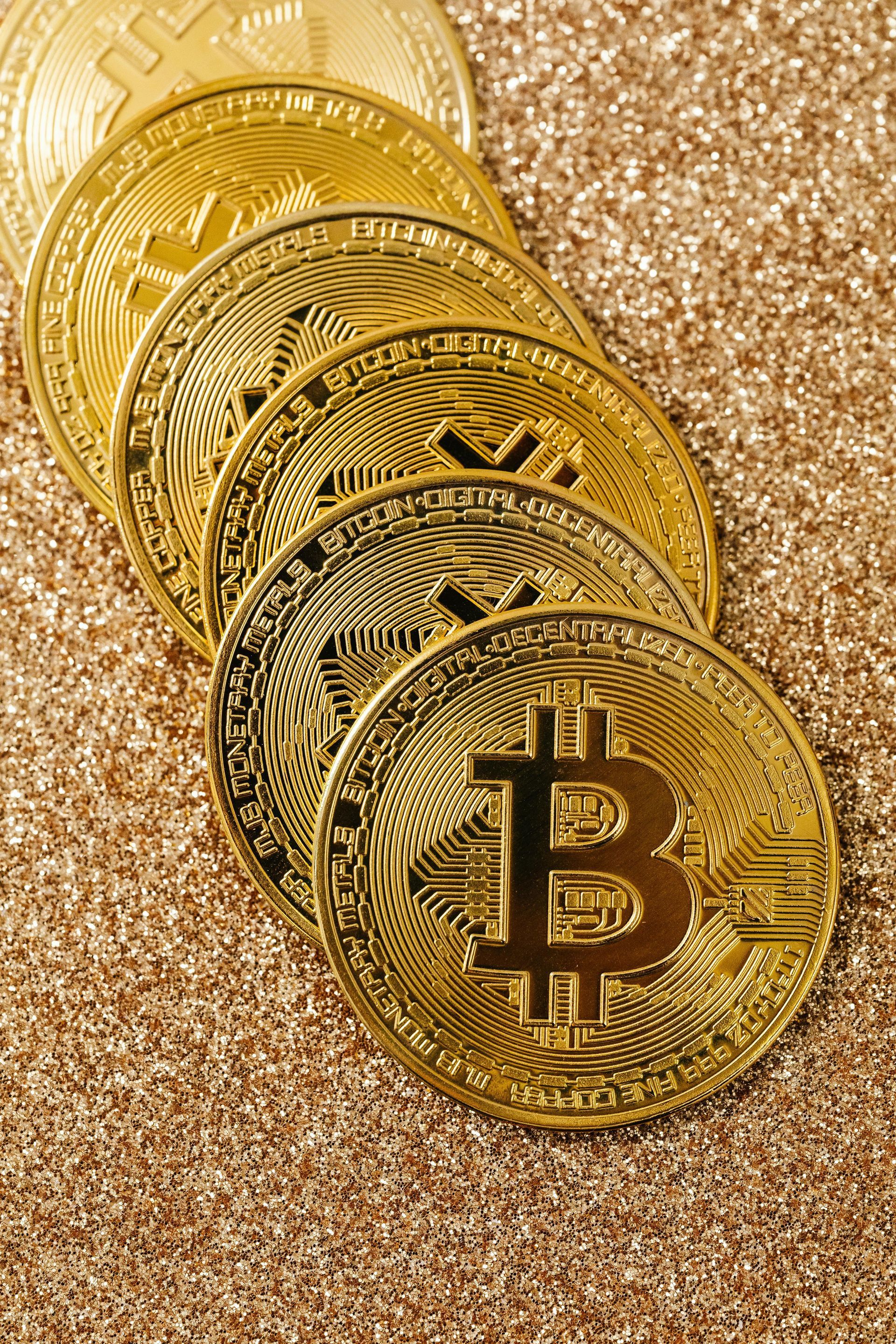 Stack of gold Bitcoin coins on a glittery gold background