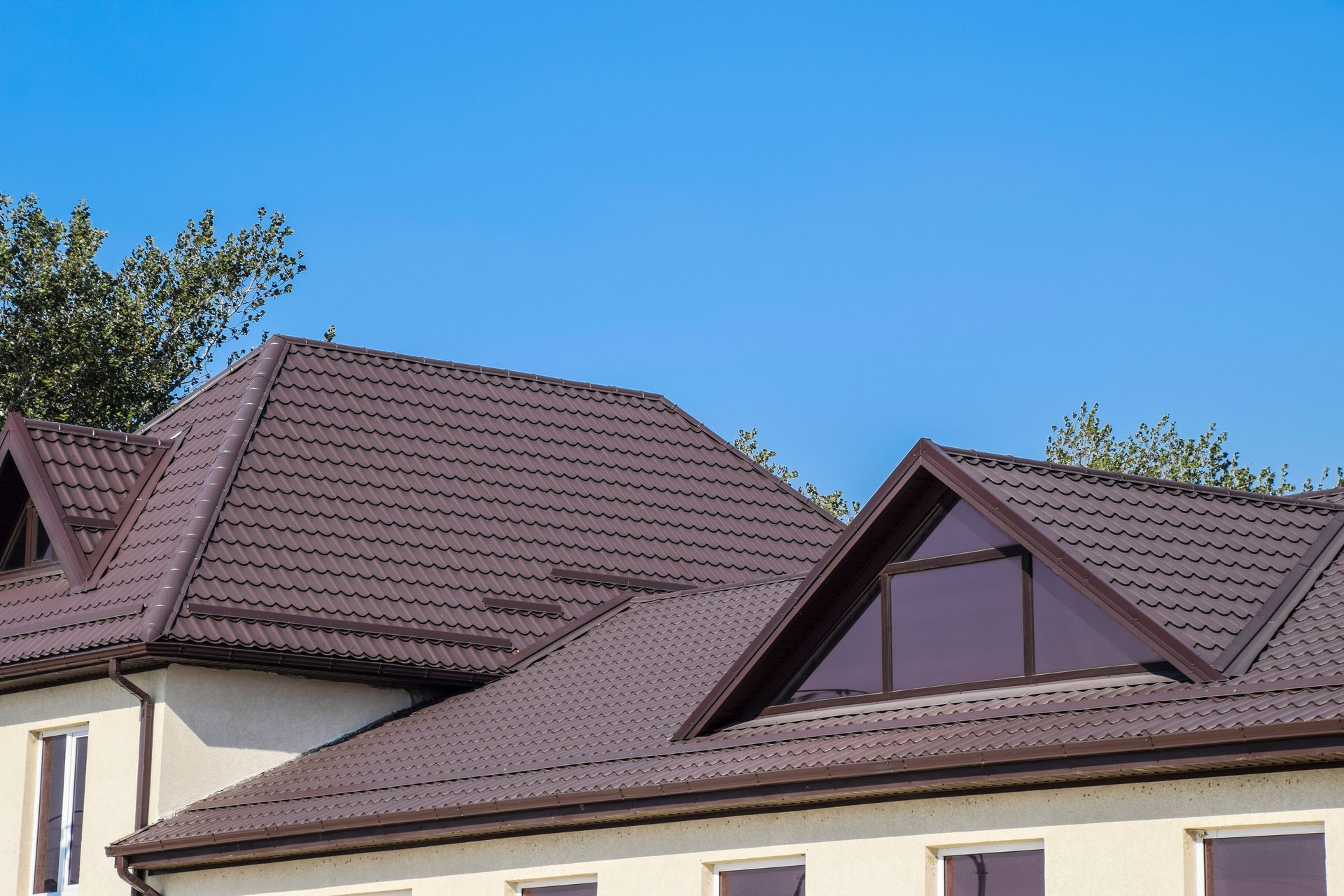 Residential rooftops with brown shingles under a clear blue sky