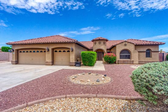 Southwestern stucco house with red tile roof, three-car garage, and desert landscaping under a blue sky Southwestern stucco house with red tile roof, three-car garage, and desert landscaping under a blue sky