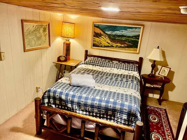 A bedroom with a bed , nightstand , lamp and curtain.