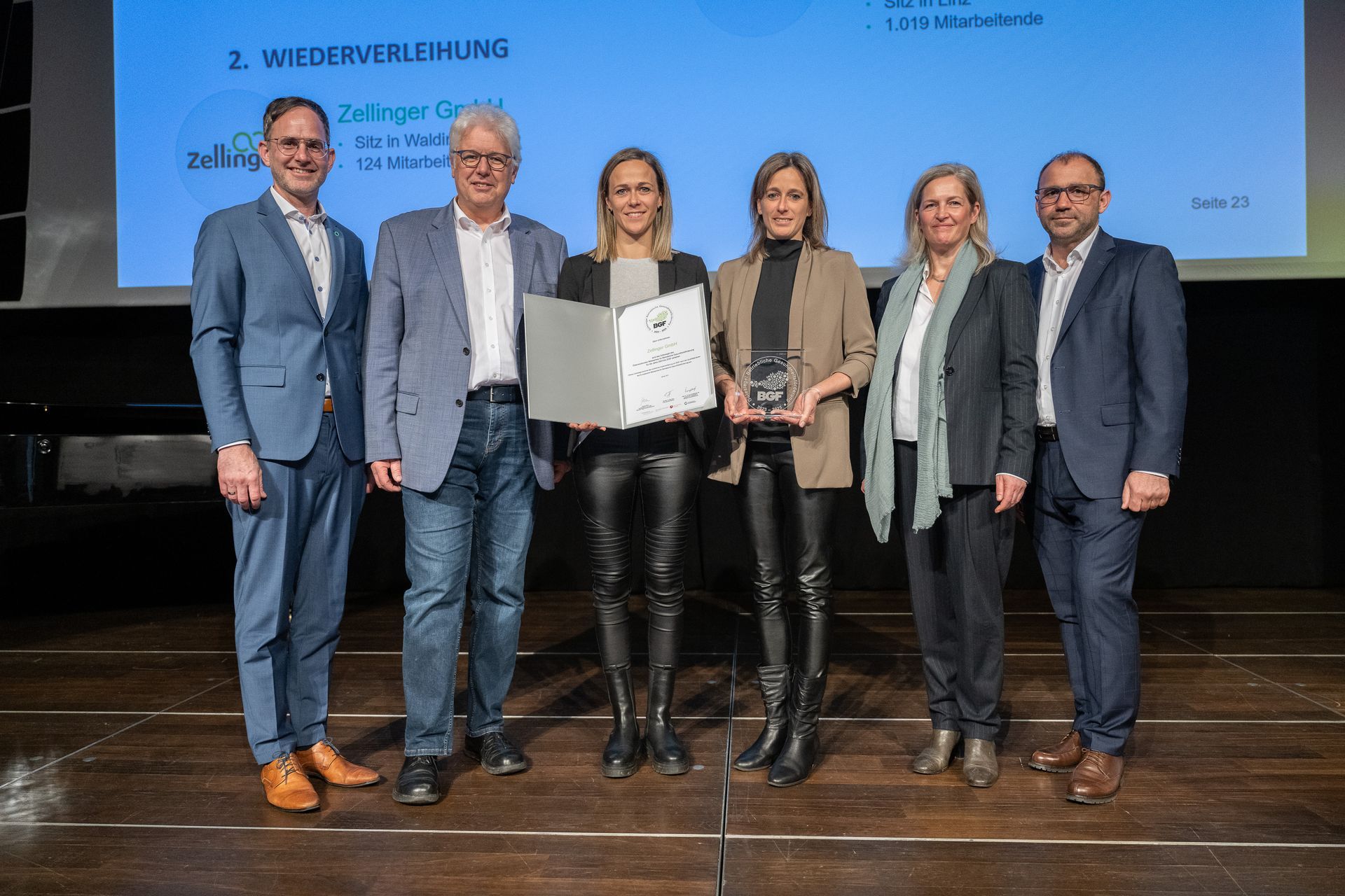 Group of people on stage holding awards and certificates.