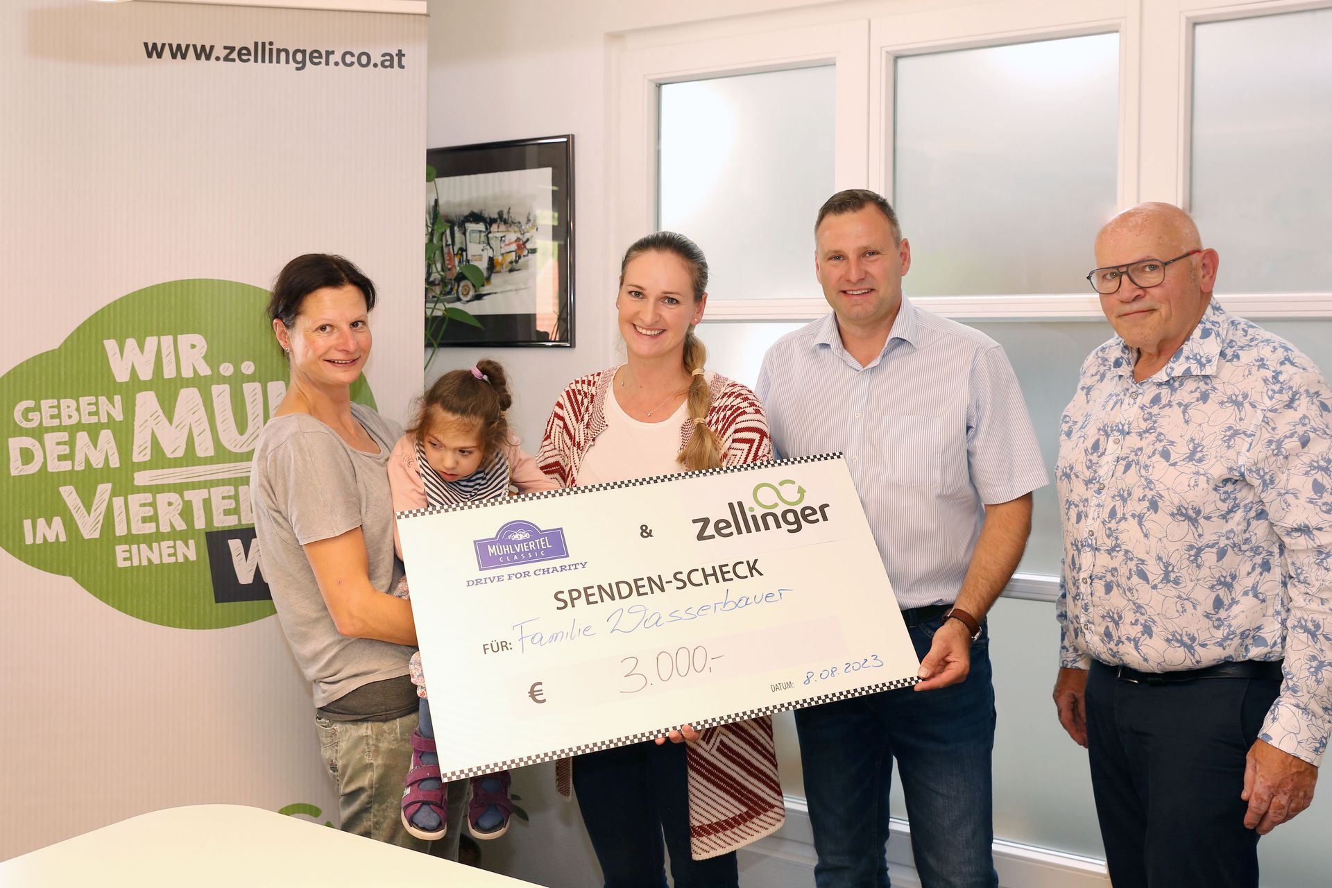 People holding a large check, likely a donation. Indoors, a woman holds a child.