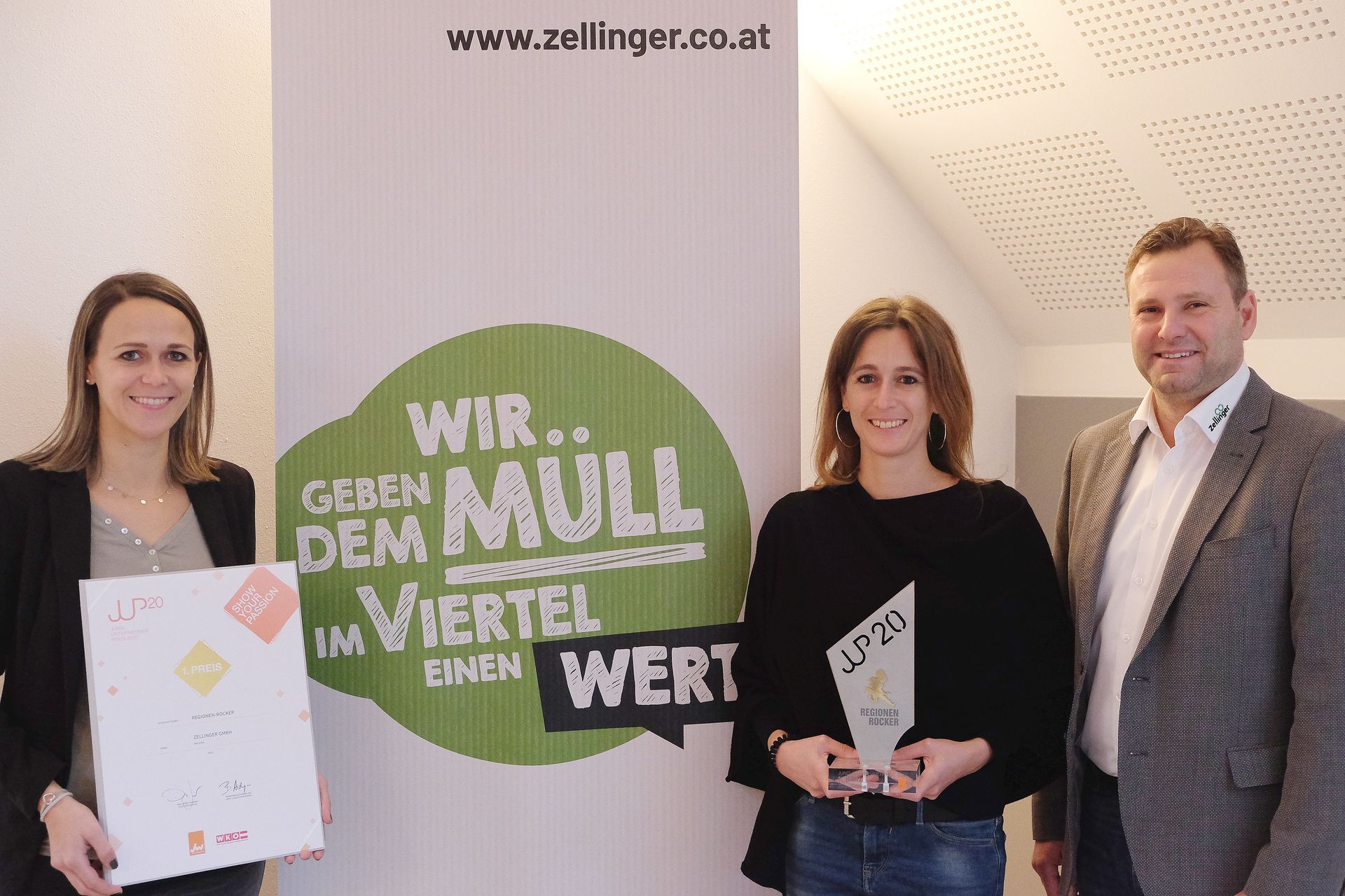 Three people stand by a banner that says 