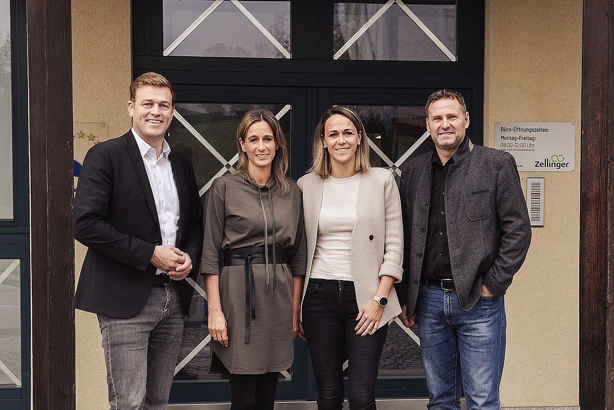 Four people standing in front of a building; two women and two men, smiling.