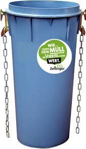 Blue trash can with attached chains. Contains a green sticker with German text.
