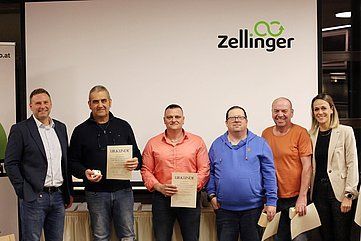 Group of people at an event with certificates and a Zelliger logo.