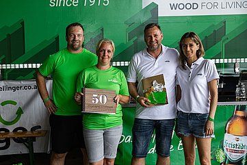 Four people smiling, holding gifts and a 