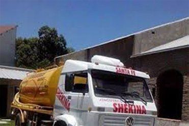 Un camión blanco con un tanque amarillo en la parte trasera está estacionado frente a un edificio.