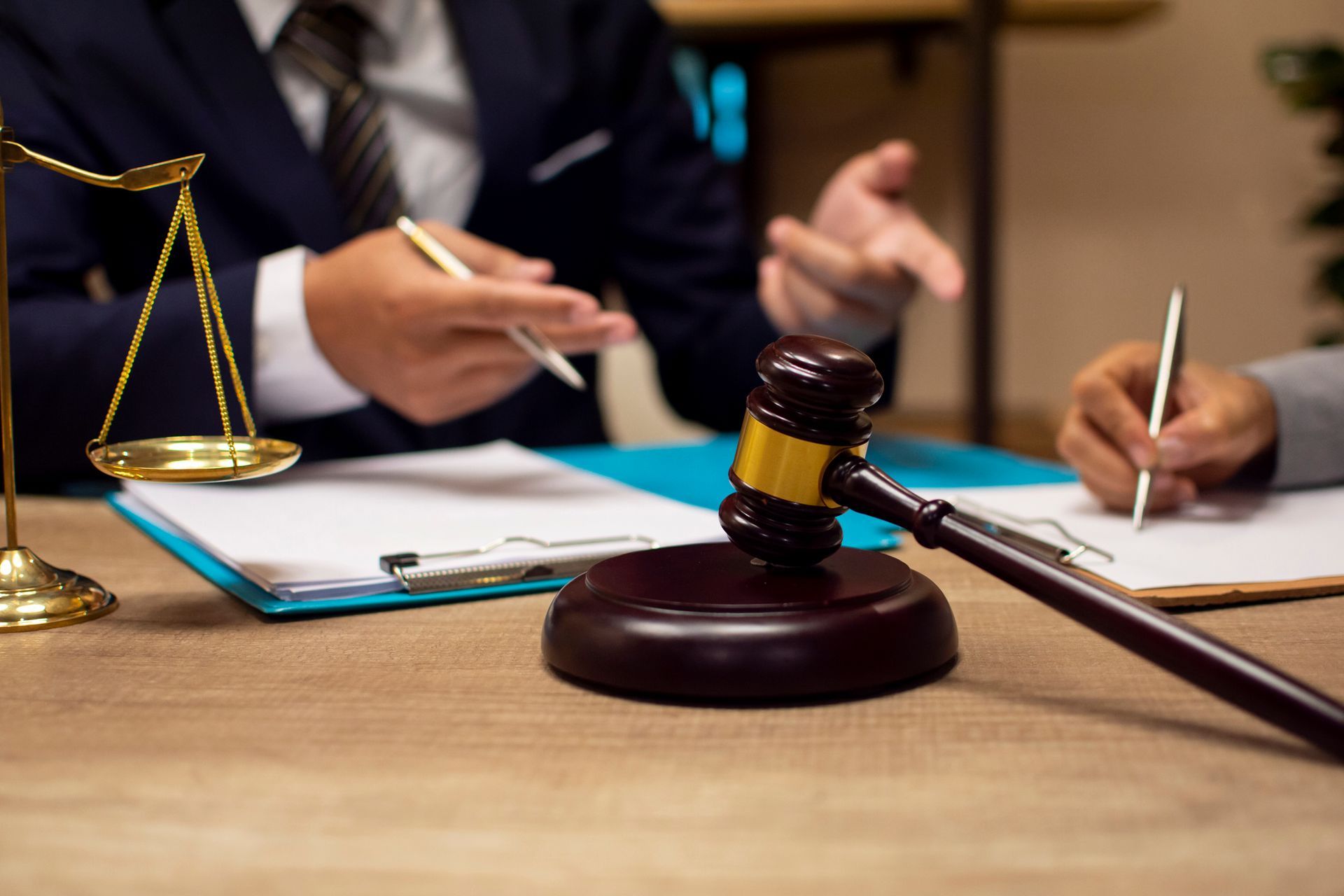Court mediation meeting with legal documents, gavel, and scales of justice on a wooden desk.