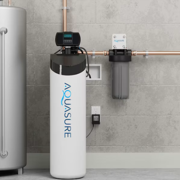 Water fills a clear glass held under a faucet in a kitchen sink.