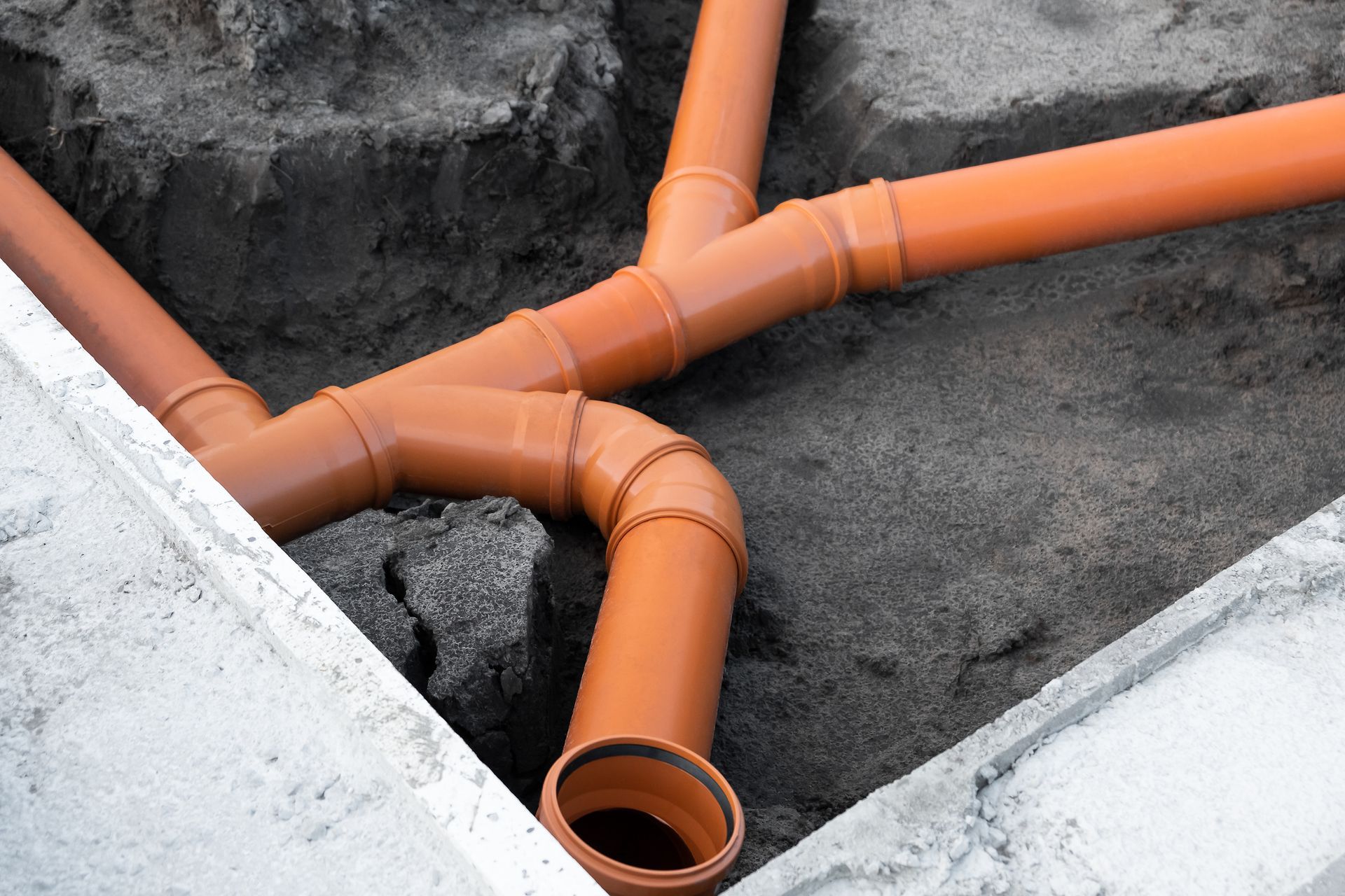Orange PVC pipes installed in a trench.