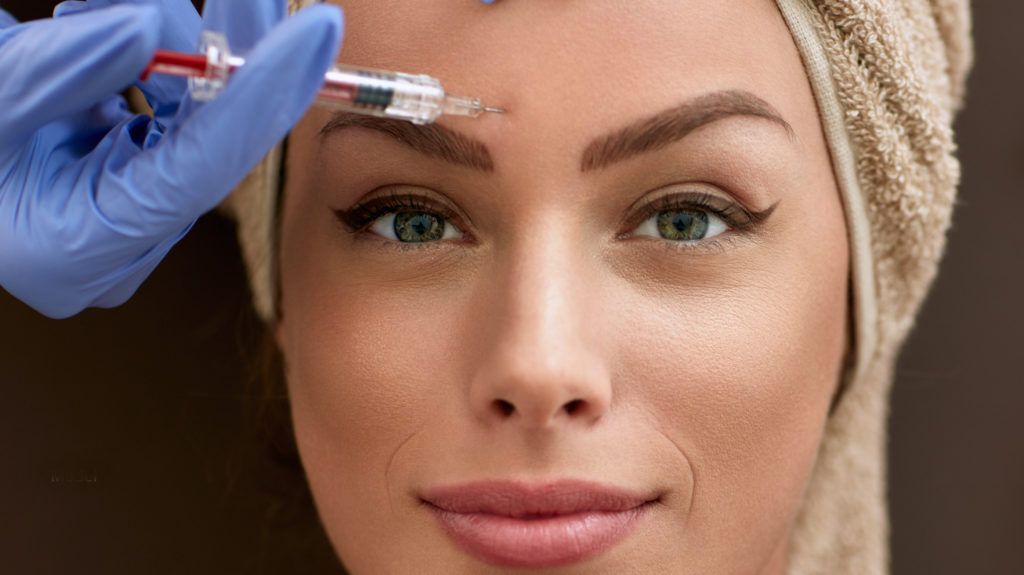 a woman is getting a botox injection on her forehead .