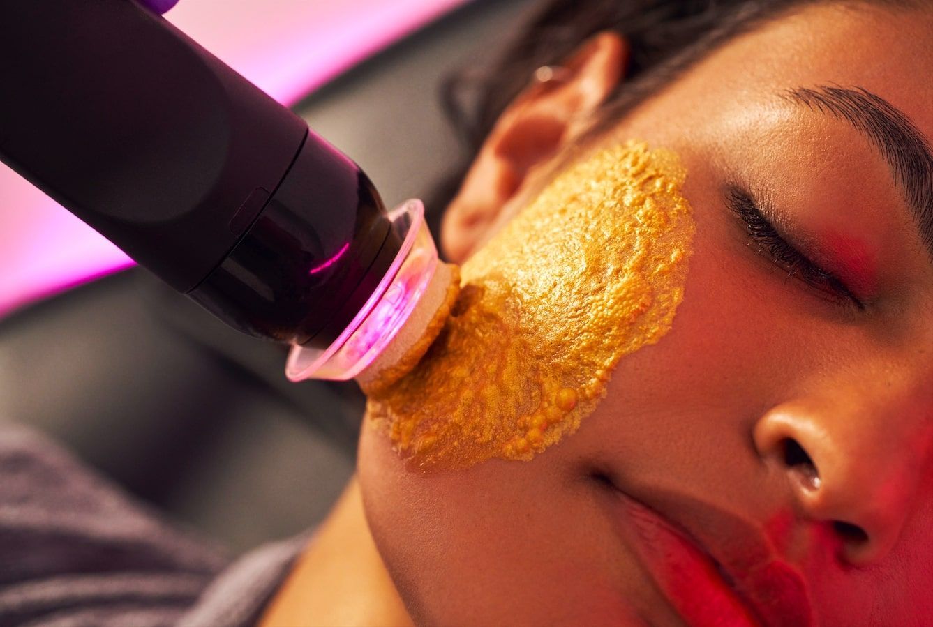 a woman is getting a facial treatment with gold powder on her face .