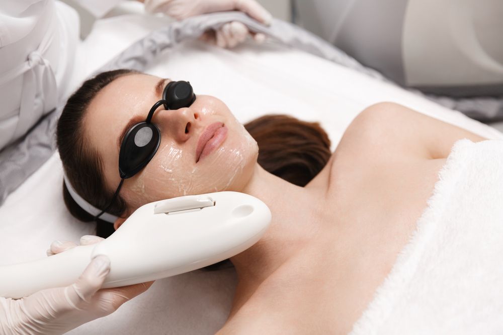 A woman is getting a laser treatment on her face.