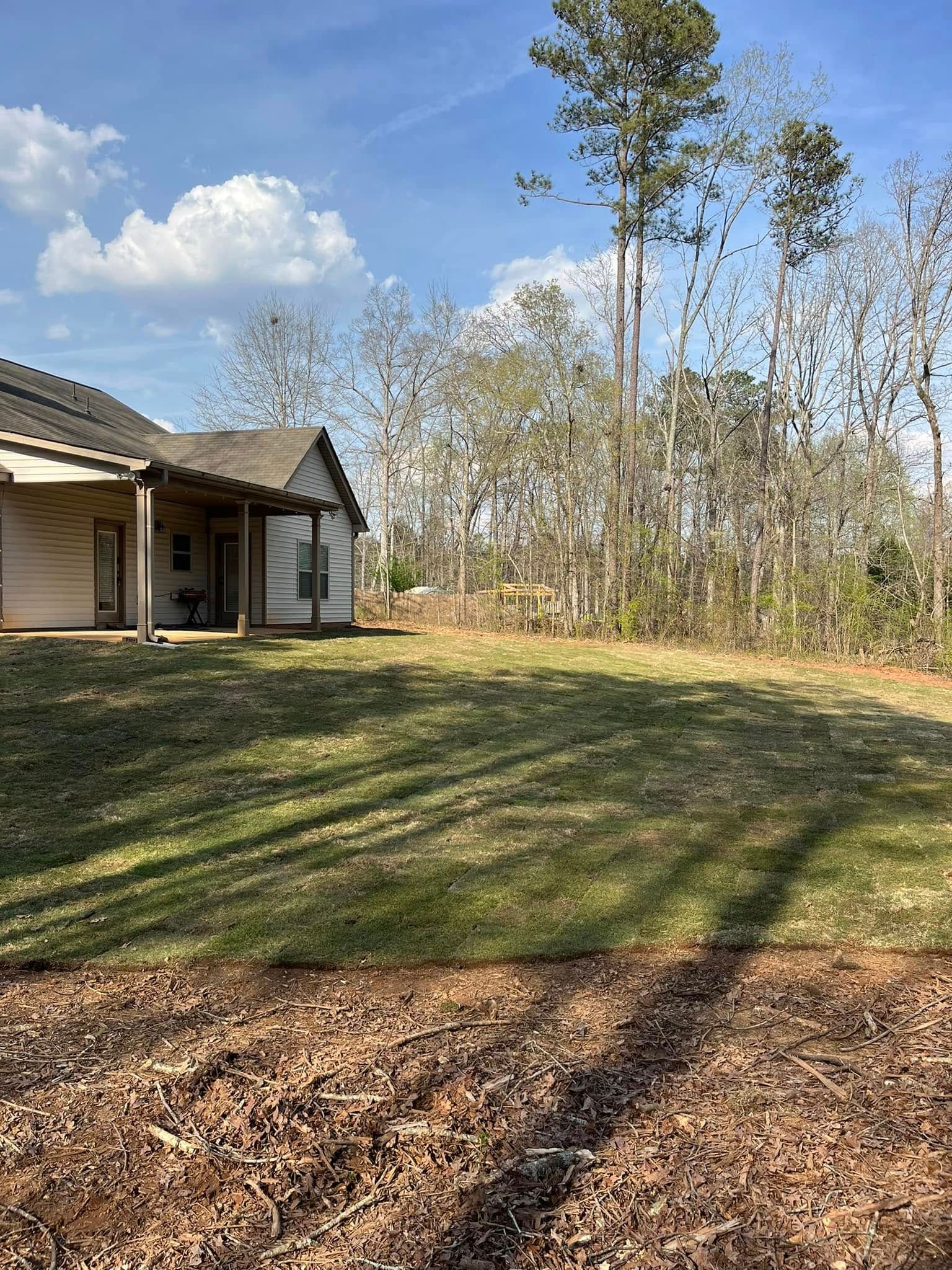 A house is sitting in the middle of a lush green field surrounded by trees.