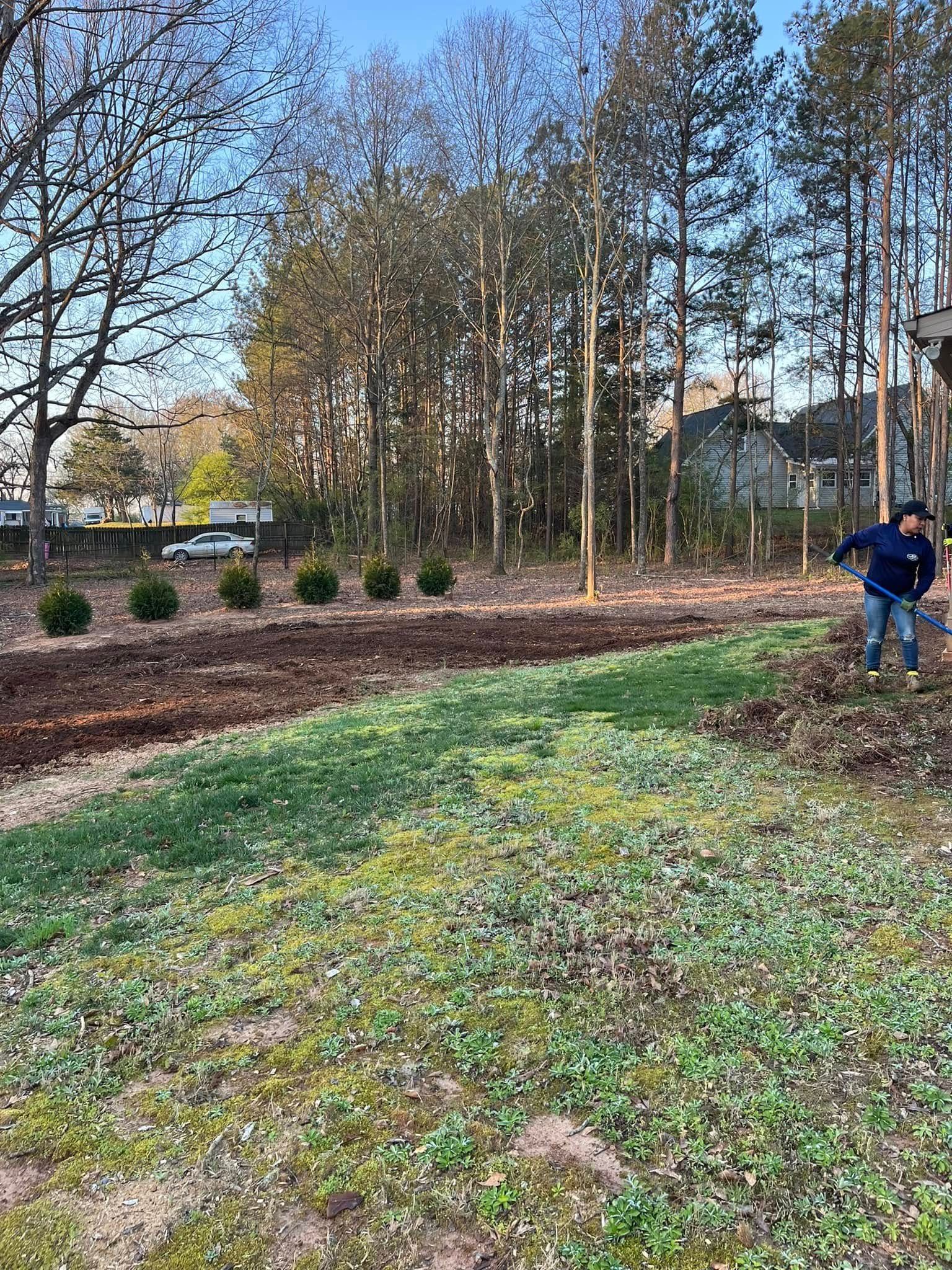 A man is standing in a field with trees in the background.