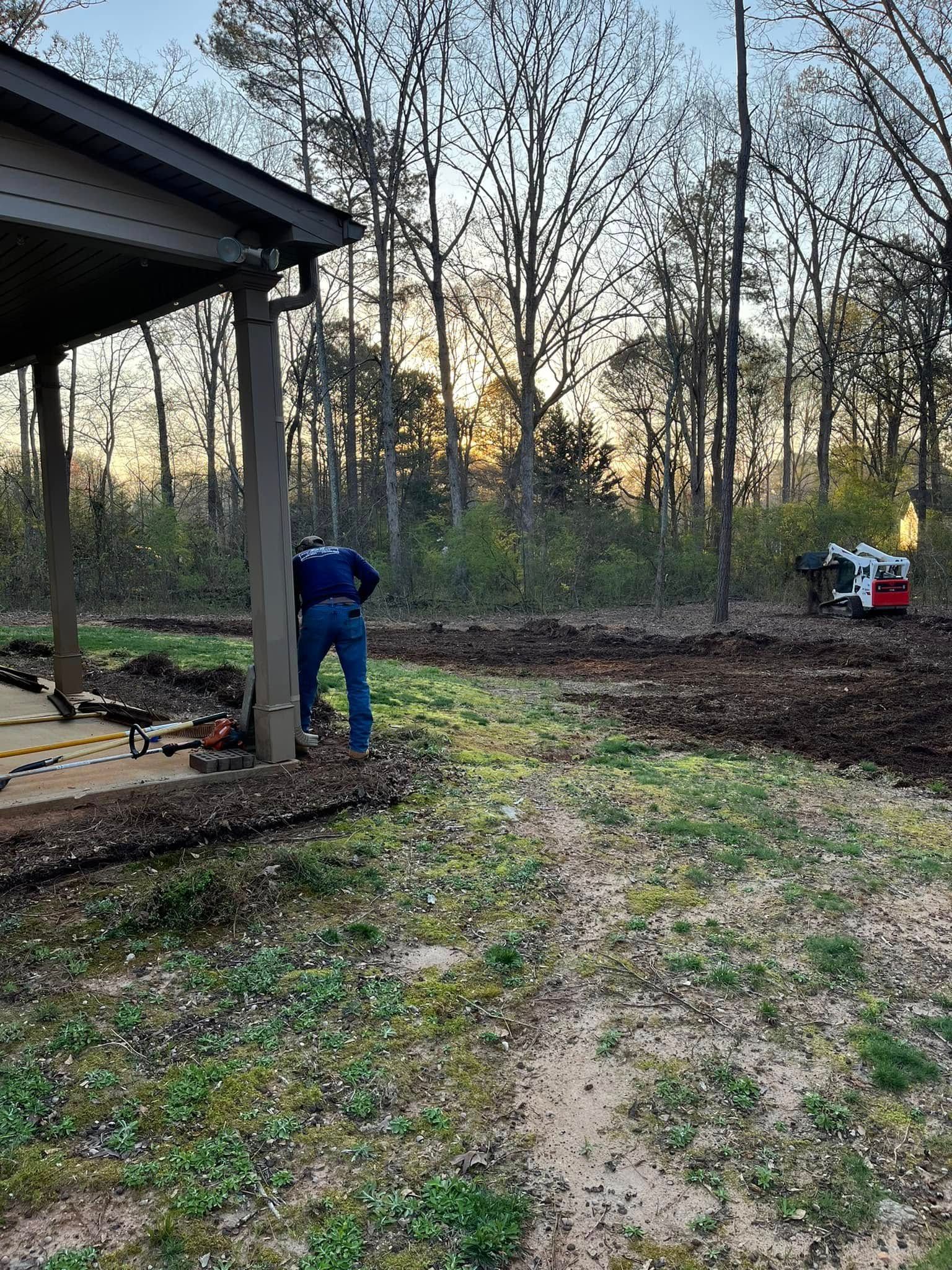 A man is digging in the dirt in front of a house.