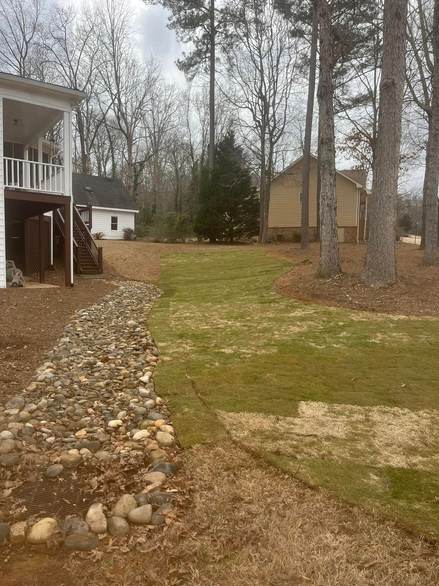 A house is sitting in the middle of a lush green field surrounded by trees.