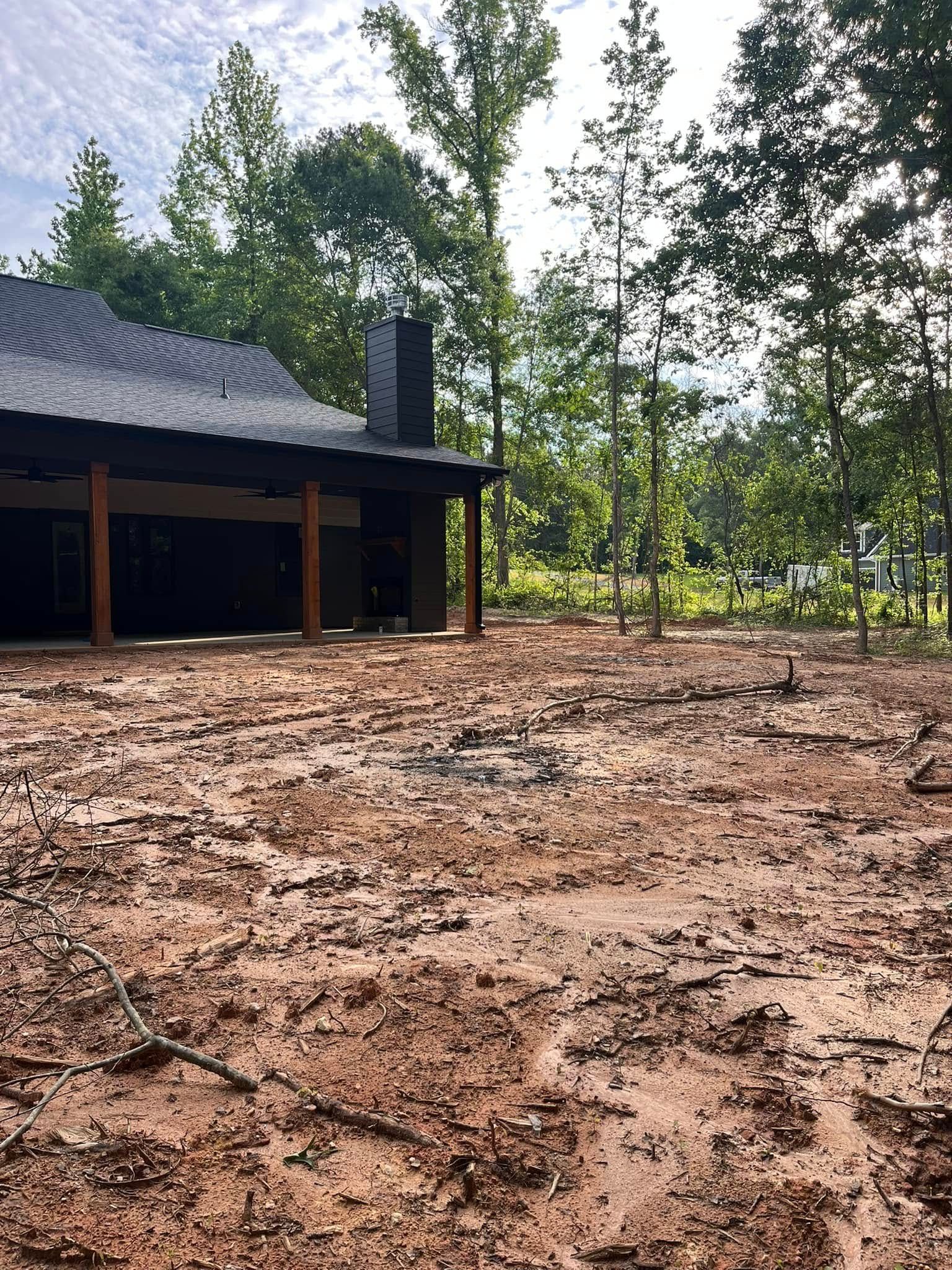 A house is sitting in the middle of a muddy field surrounded by trees.