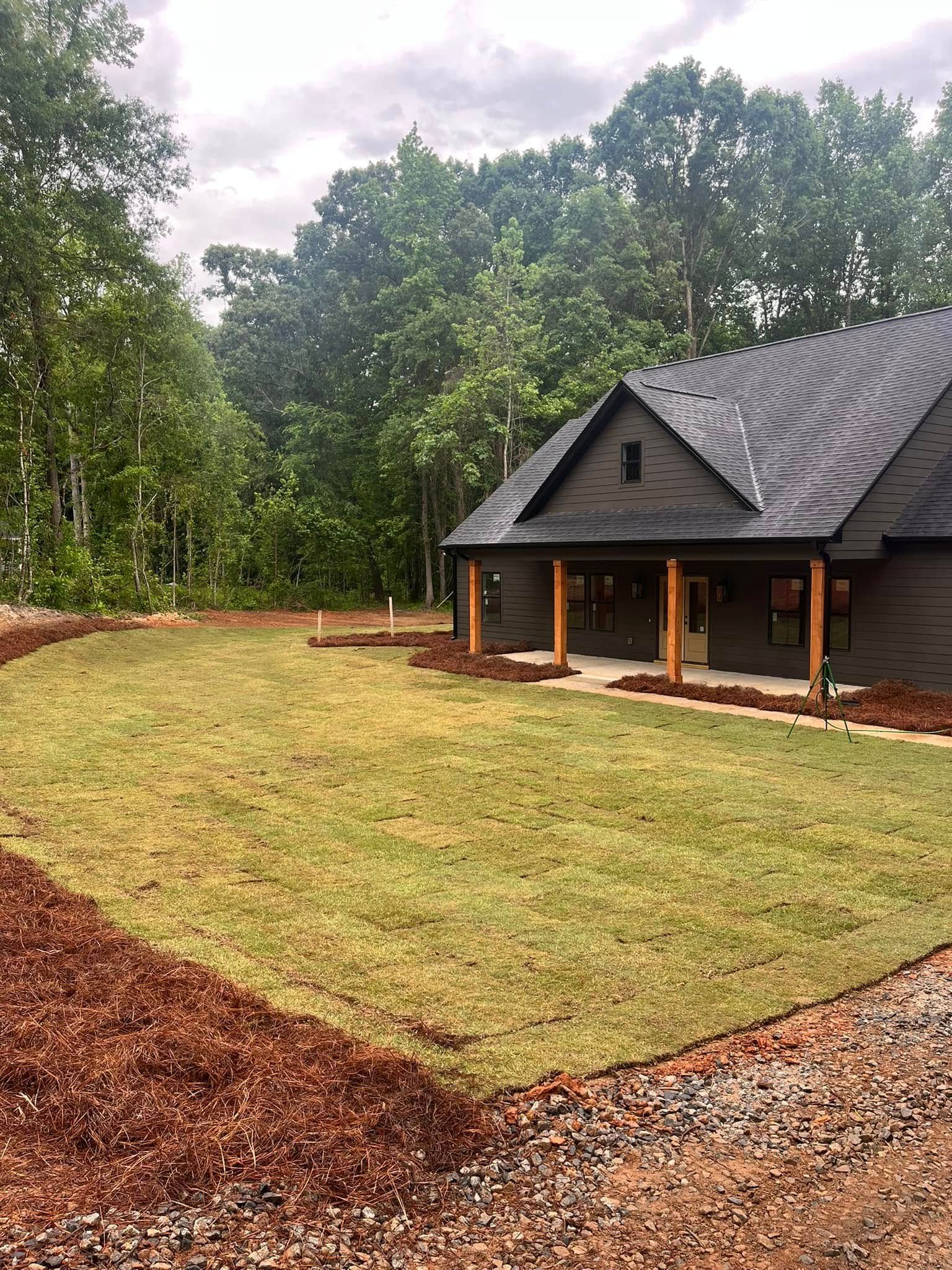 A house with a large lawn in front of it surrounded by trees.