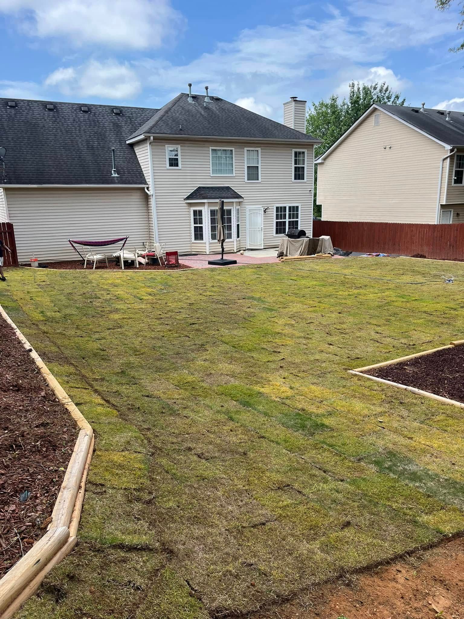 A backyard with a large lawn and a house in the background.