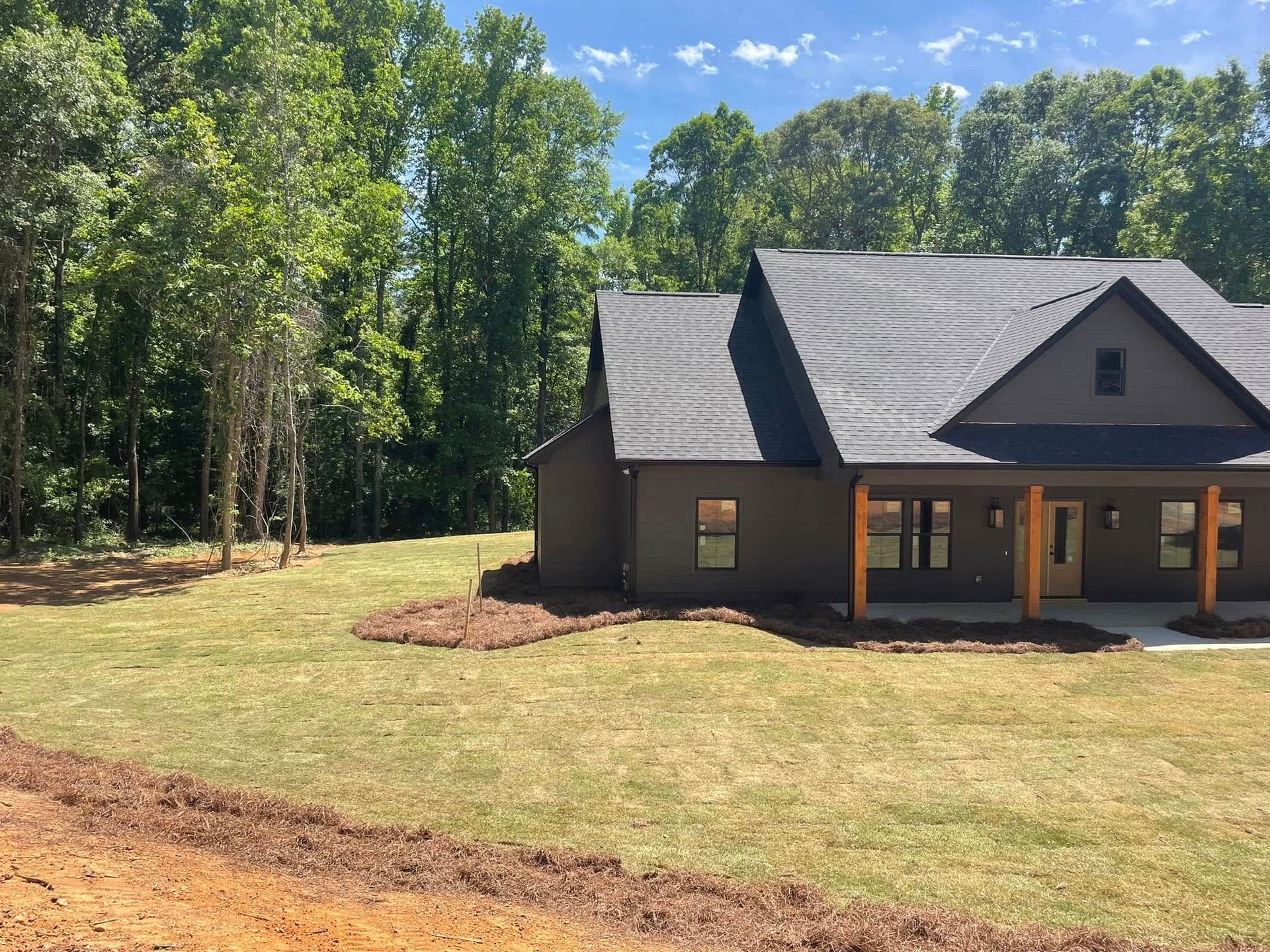 A house is sitting in the middle of a lush green field surrounded by trees.