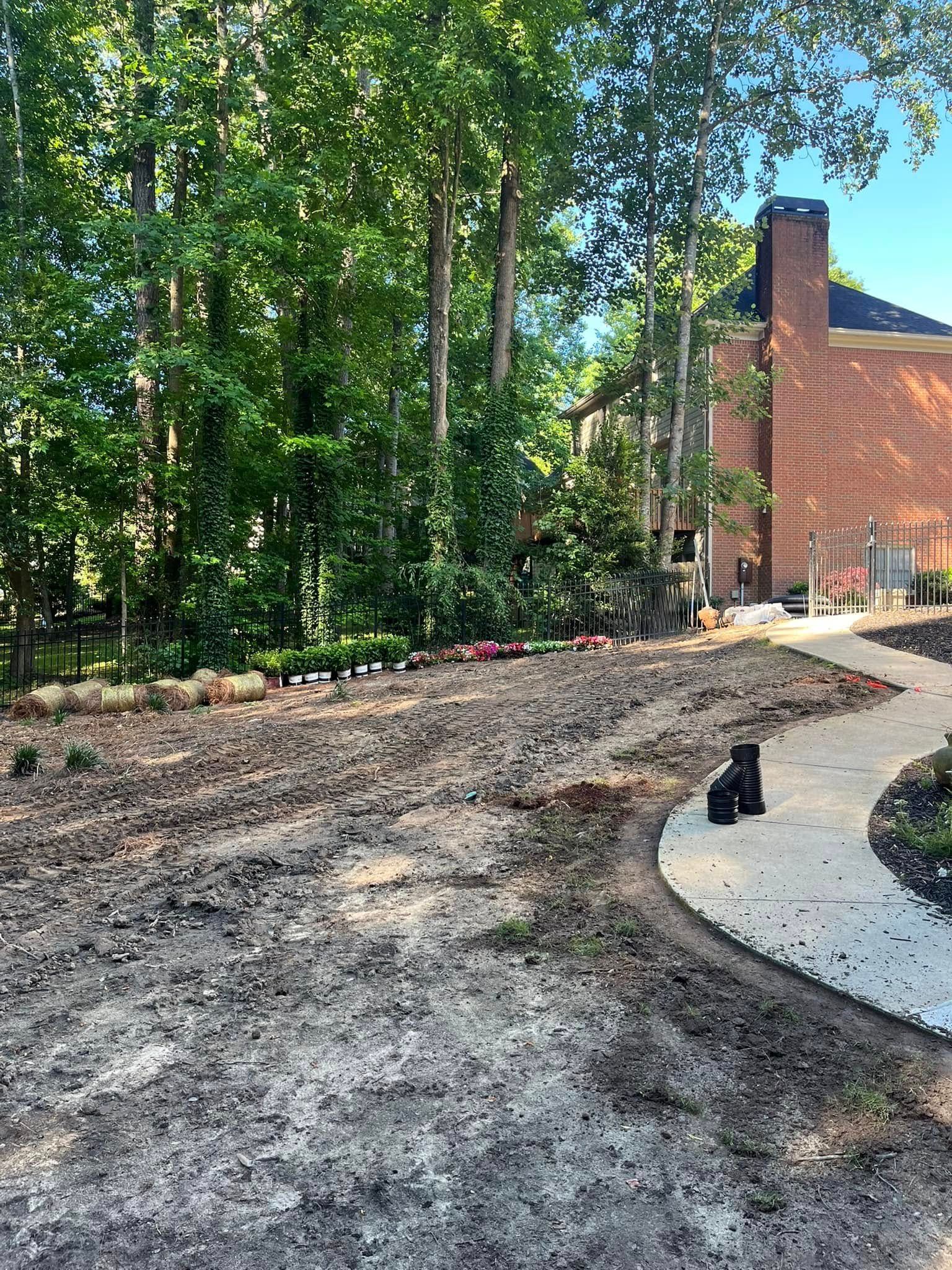 A dirt path leading to a brick house in the woods.