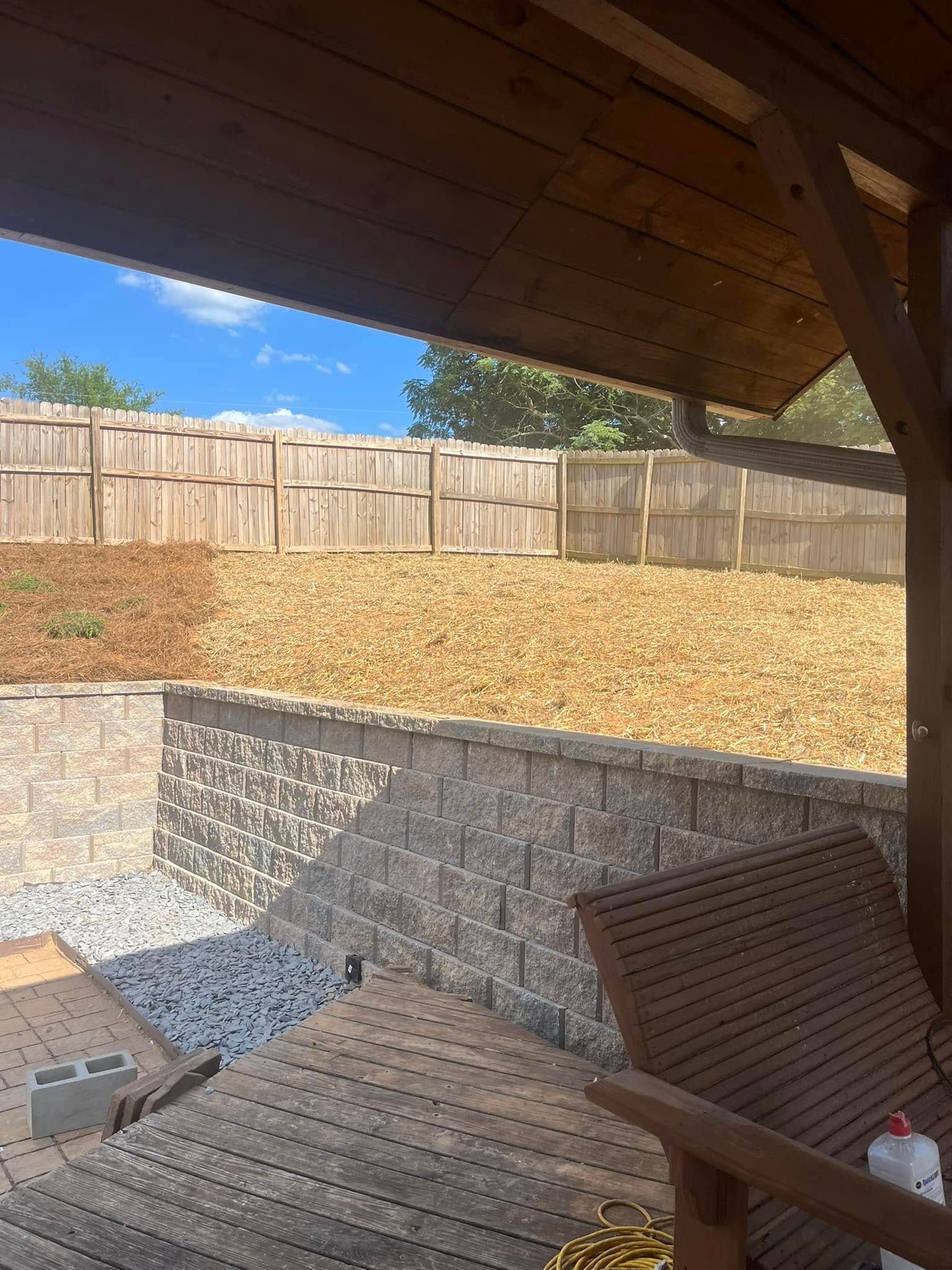 A wooden deck with a bench and a fence in the background.
