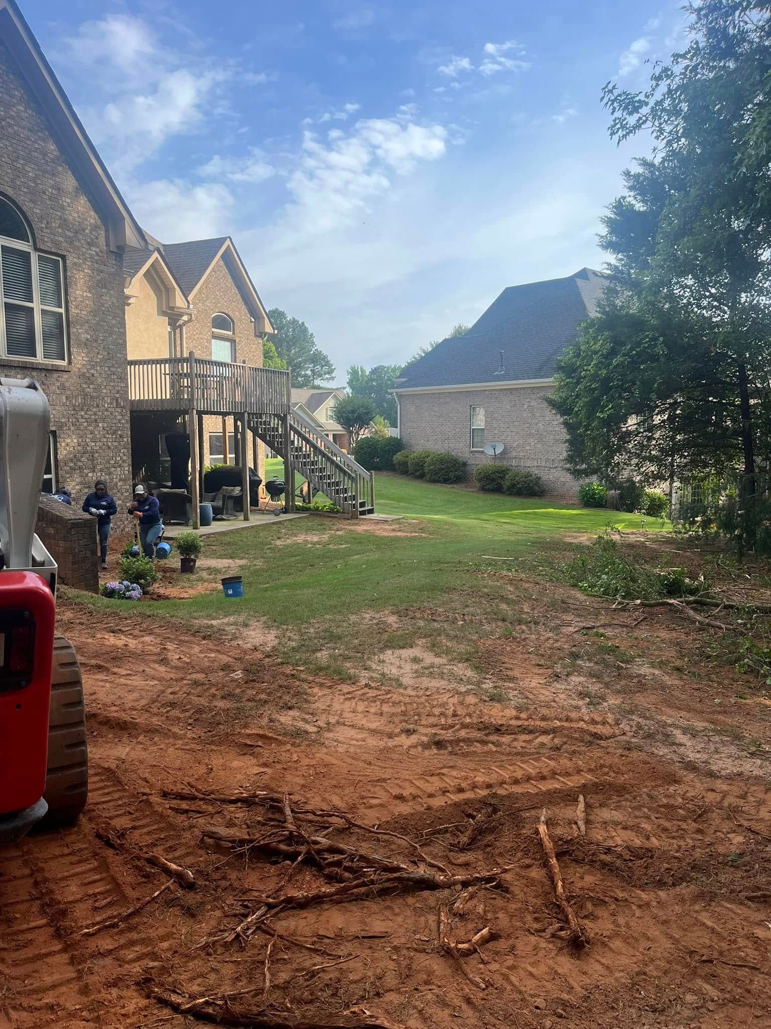 A bobcat is sitting in the dirt in front of a house.