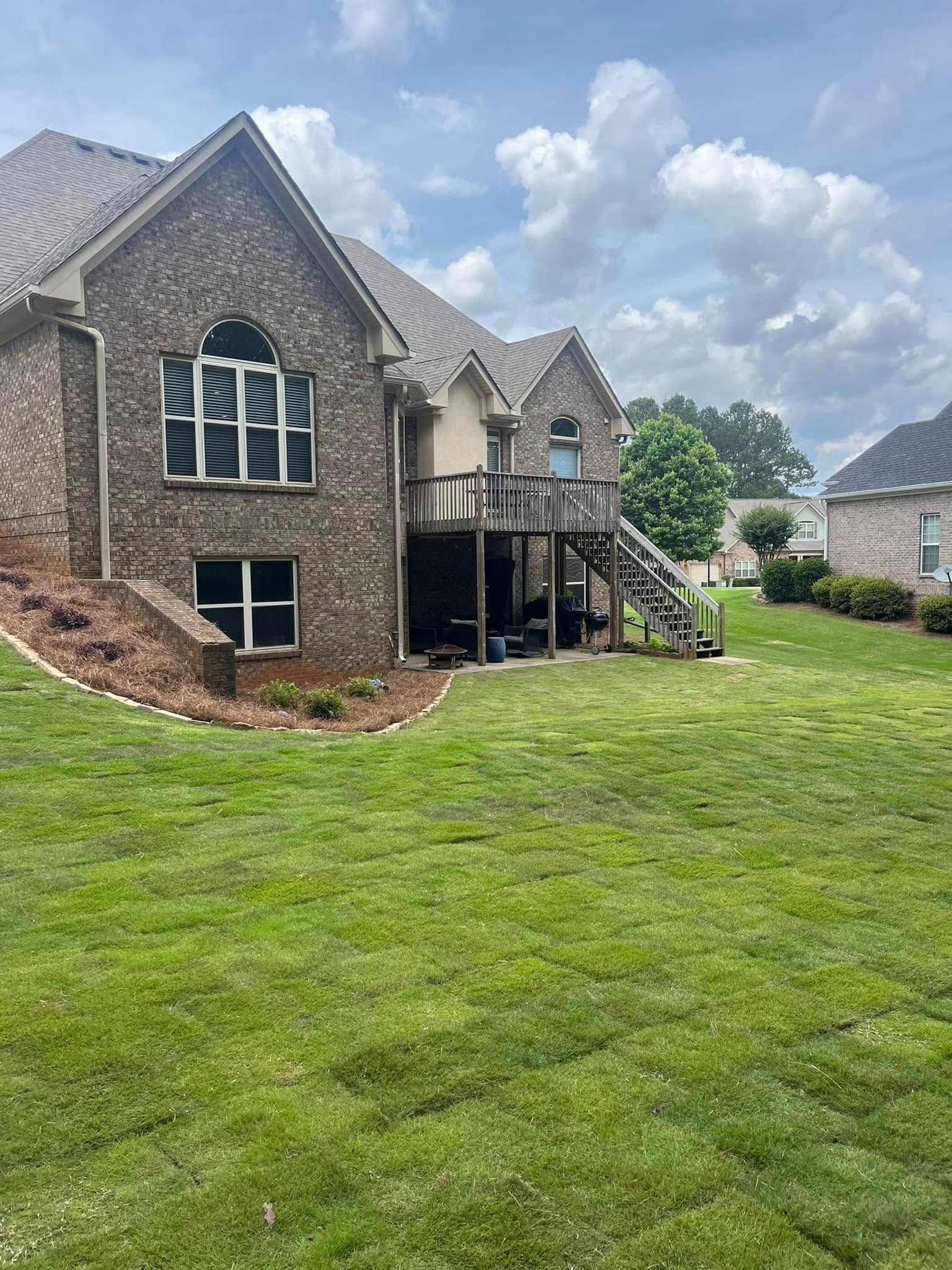 A large brick house with a large lawn in front of it.