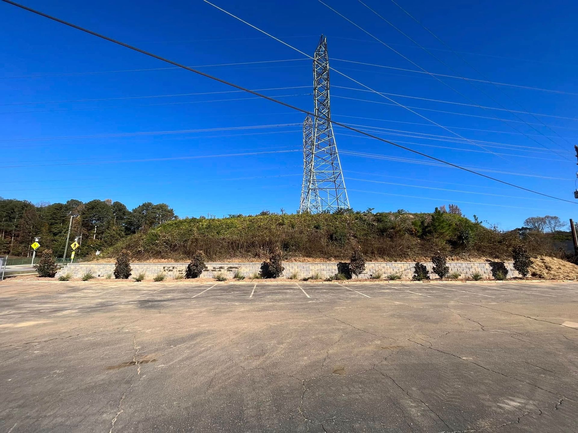 A large power tower is sitting on top of a hill in the middle of a parking lot.