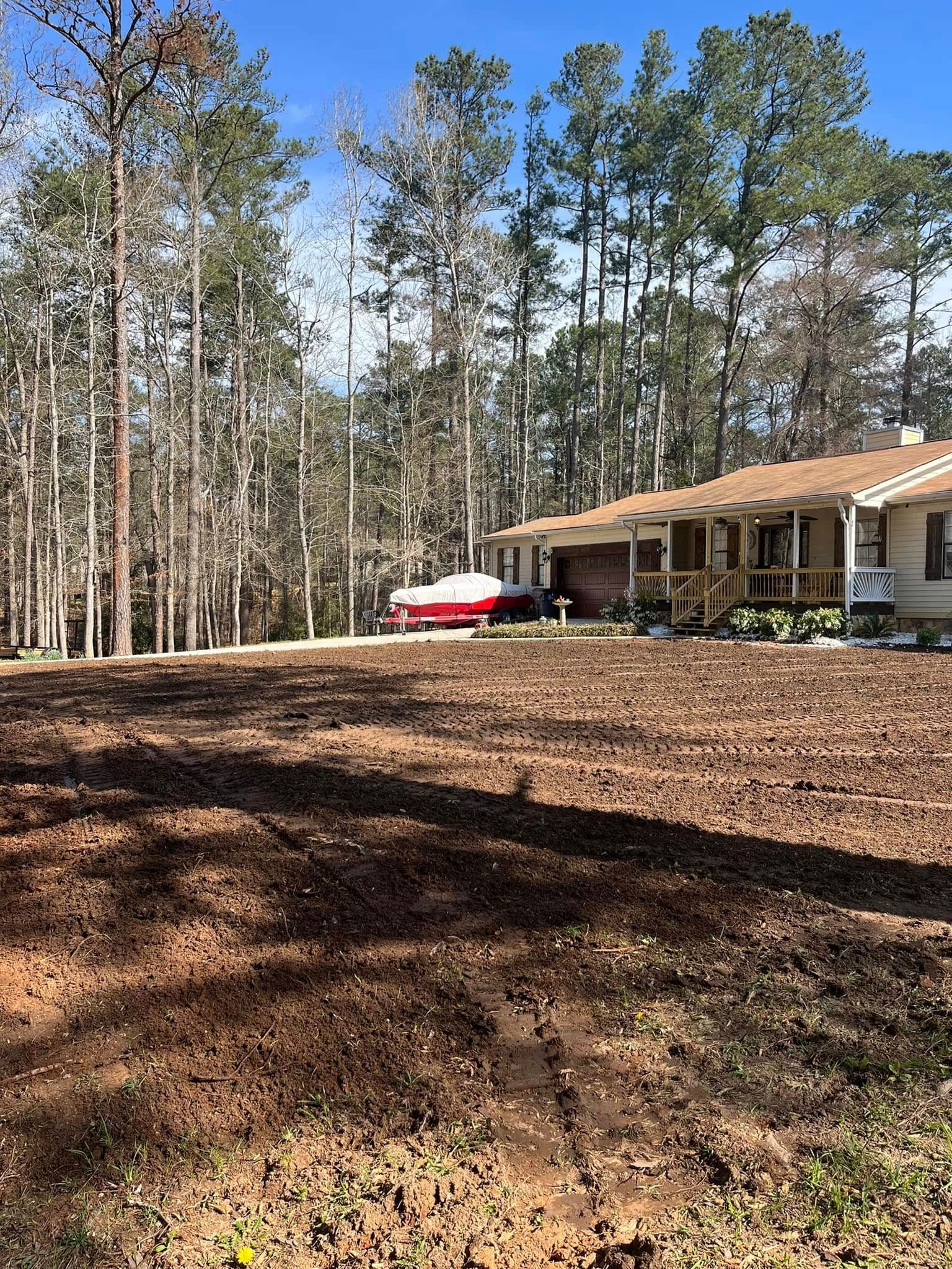 A house is sitting on top of a dirt field in the middle of a forest.