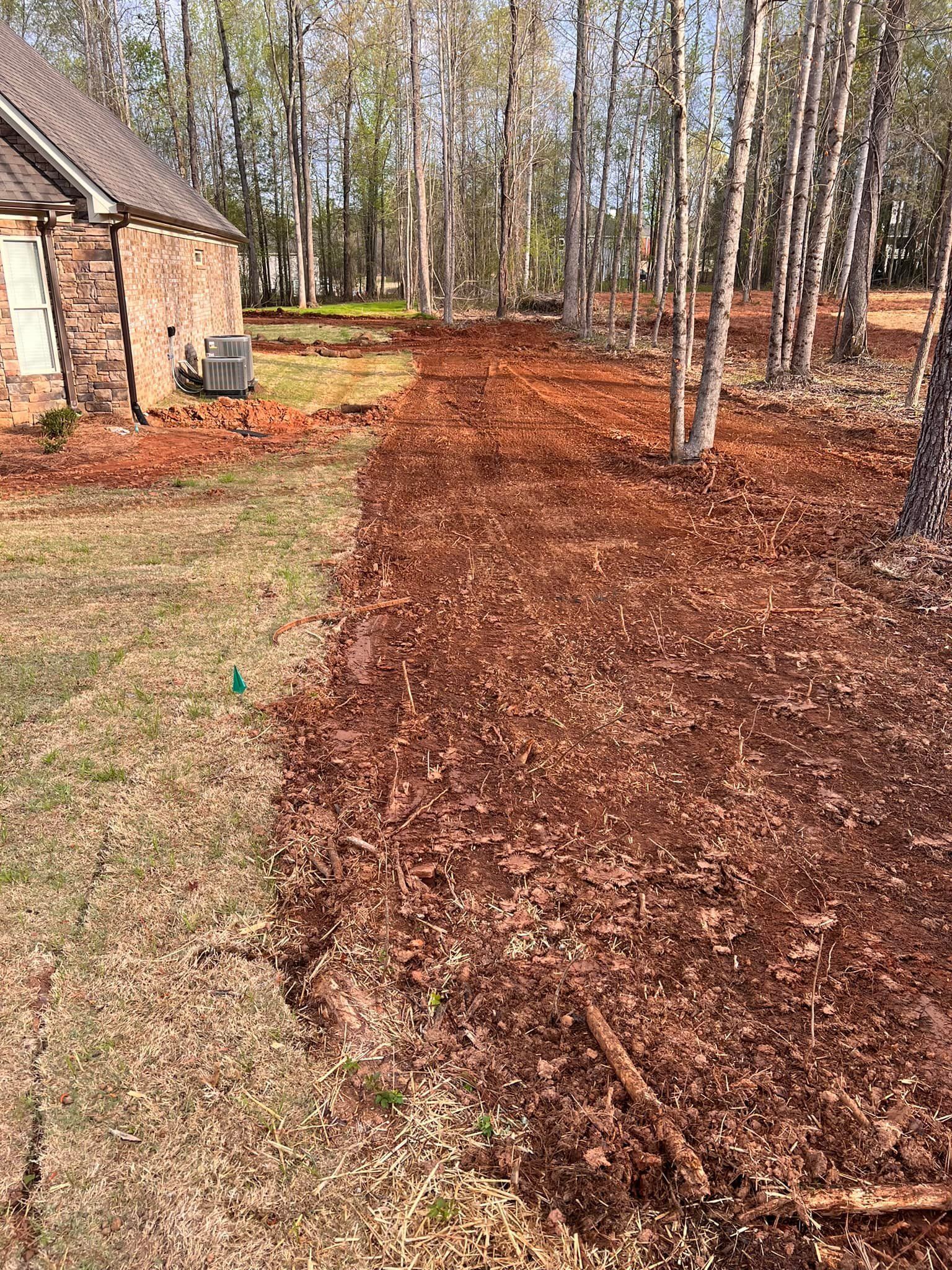There is a house in the background and a lot of mulch in the foreground.