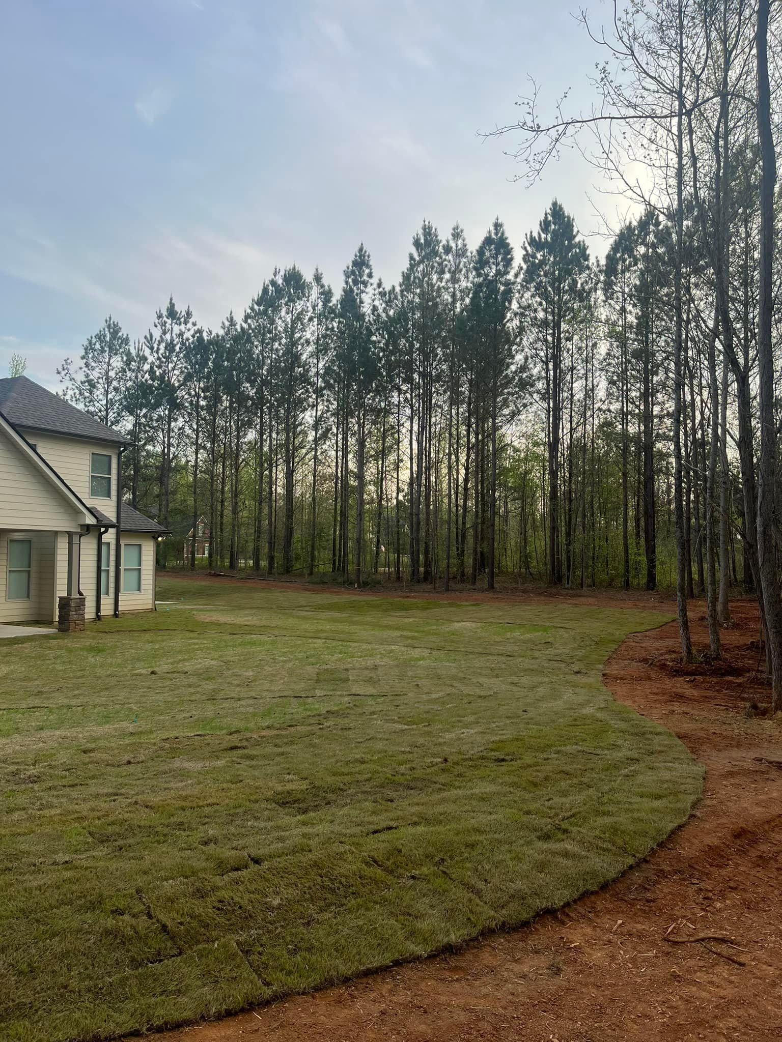 A house is sitting in the middle of a lush green field surrounded by trees.