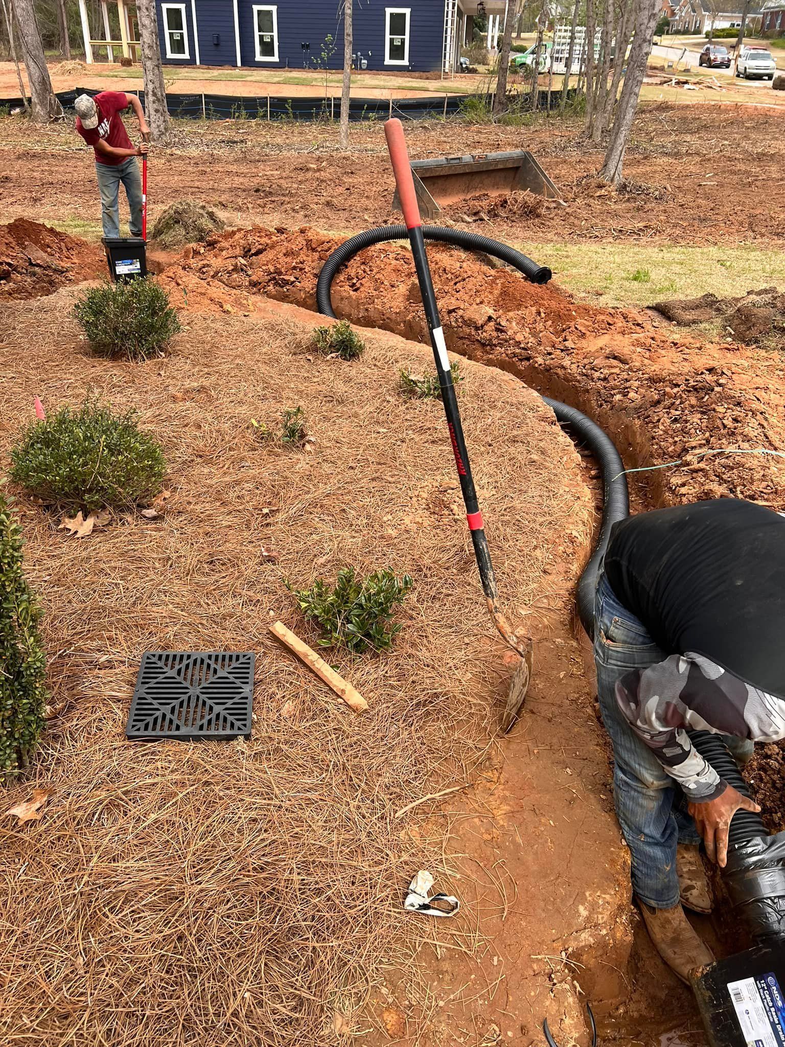 A man is digging a trench in the dirt in a garden.