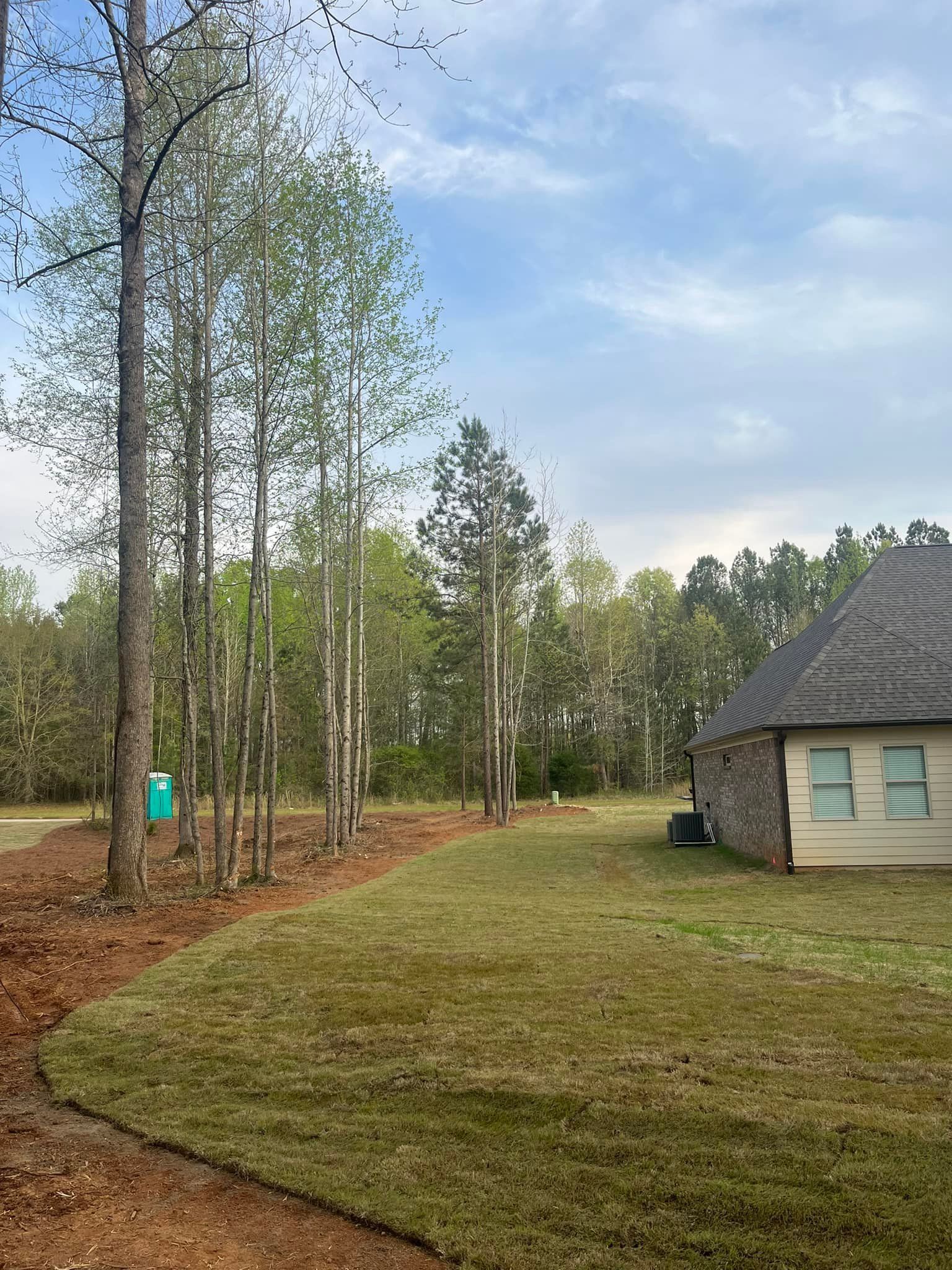 A house is sitting in the middle of a lush green field surrounded by trees.