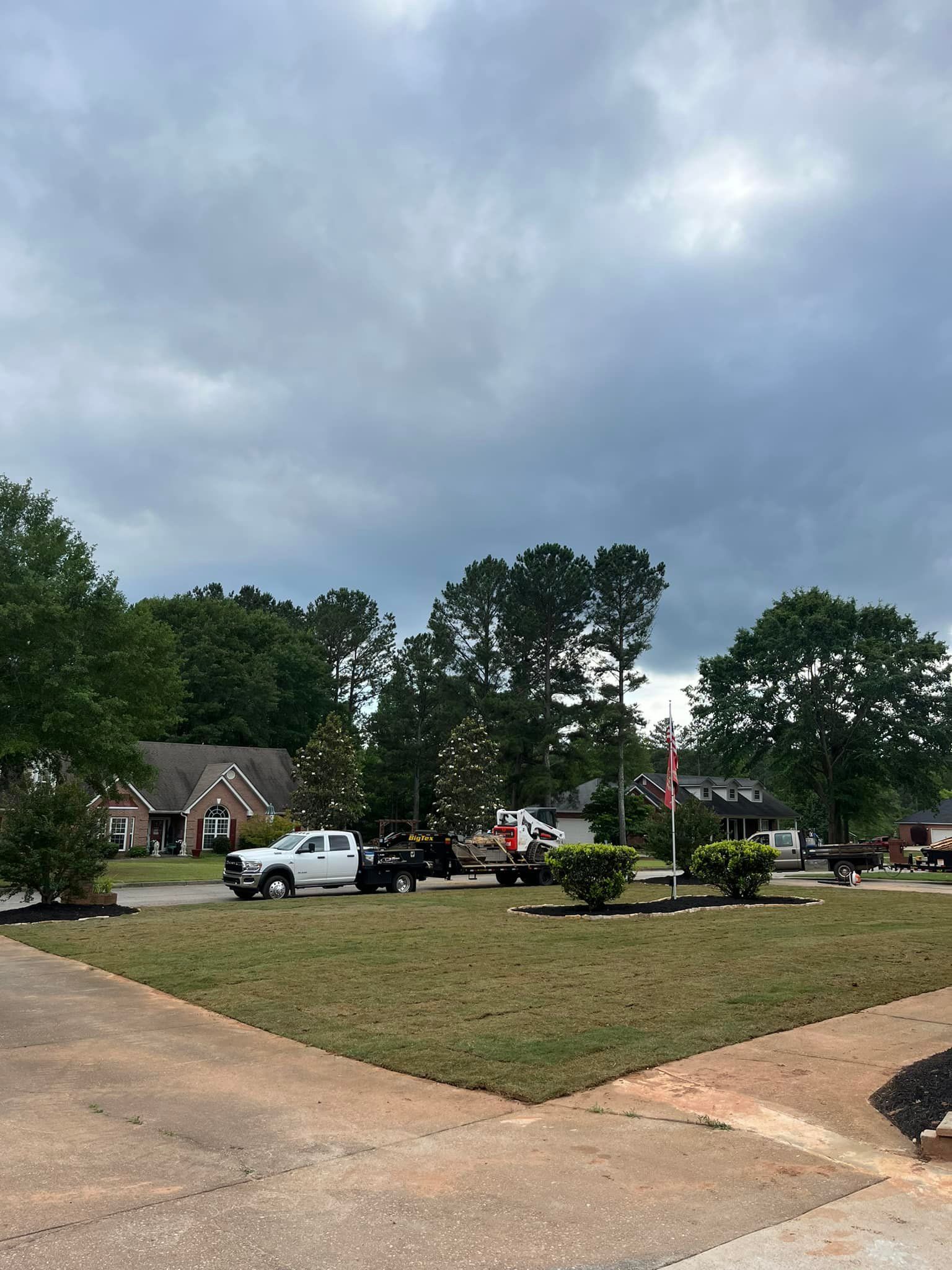 A couple of trucks are parked in a grassy field in front of a house.
