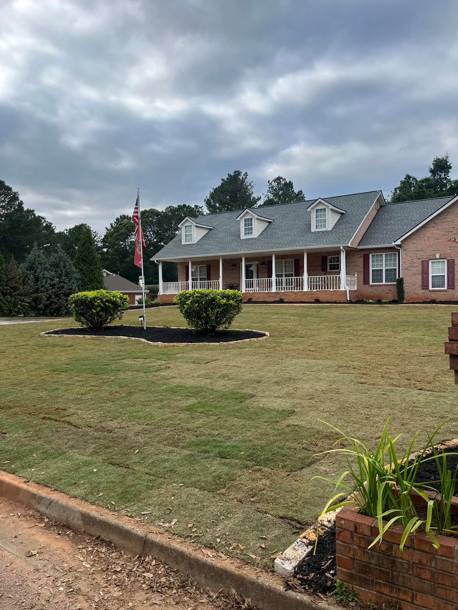 A large brick house with a large lawn in front of it.
