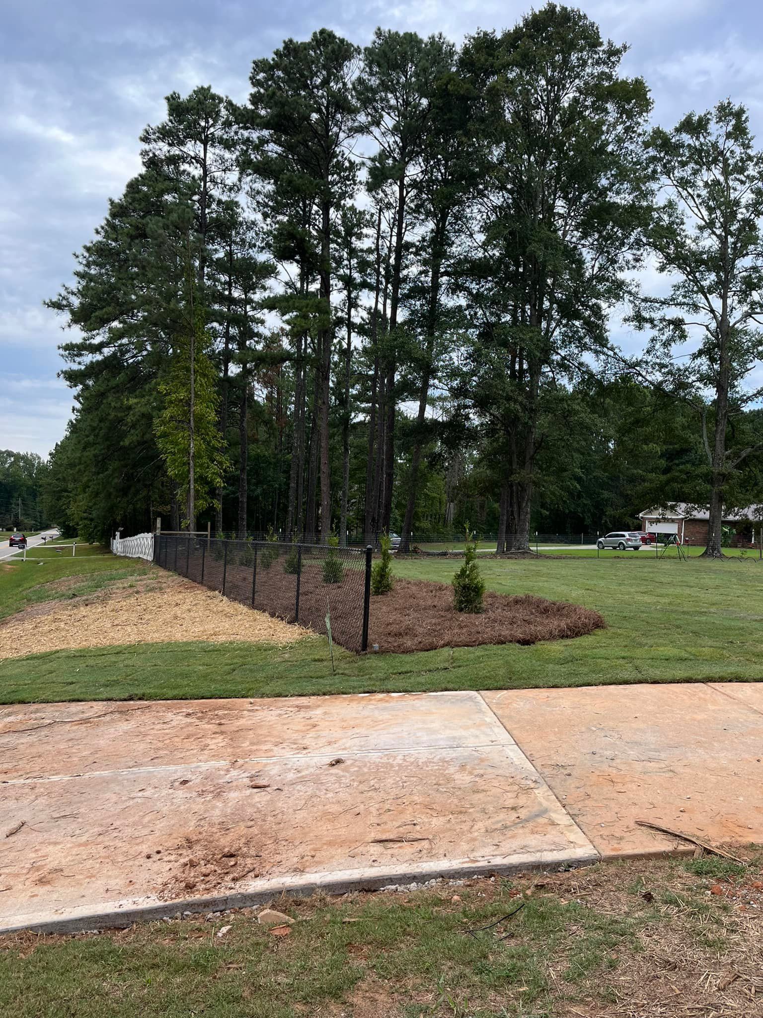 A concrete walkway leading to a grassy field with trees in the background.