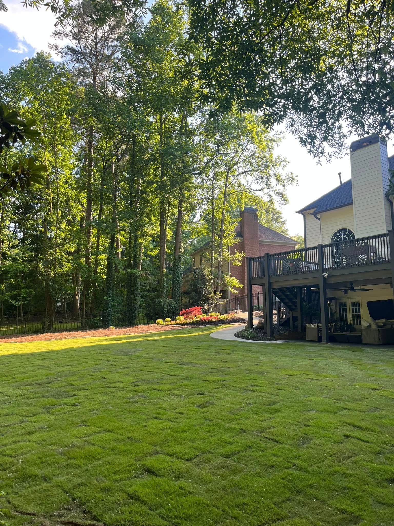 A large lush green lawn in front of a house with a deck.