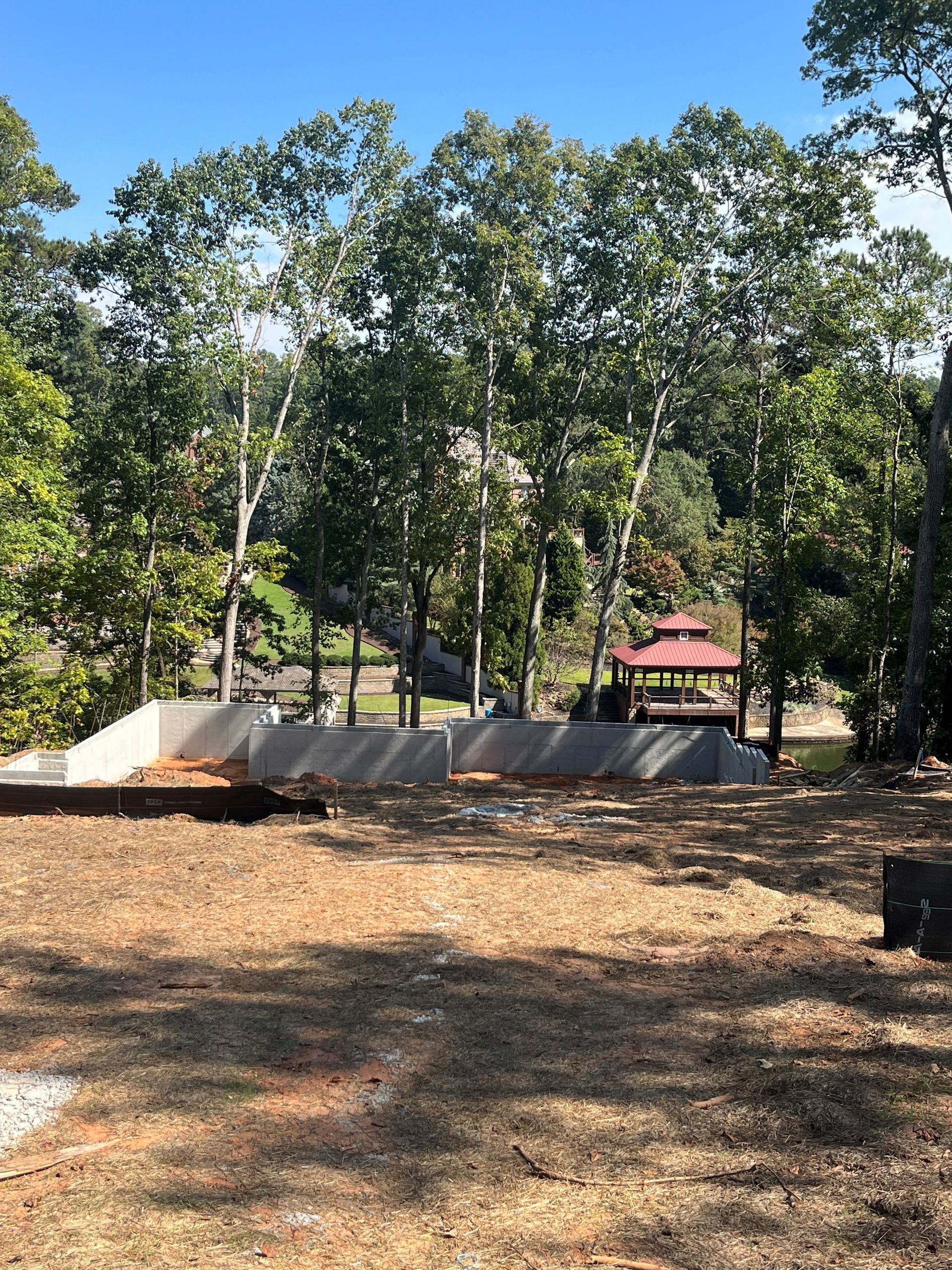 A dirt field with trees in the background and a gazebo in the background.