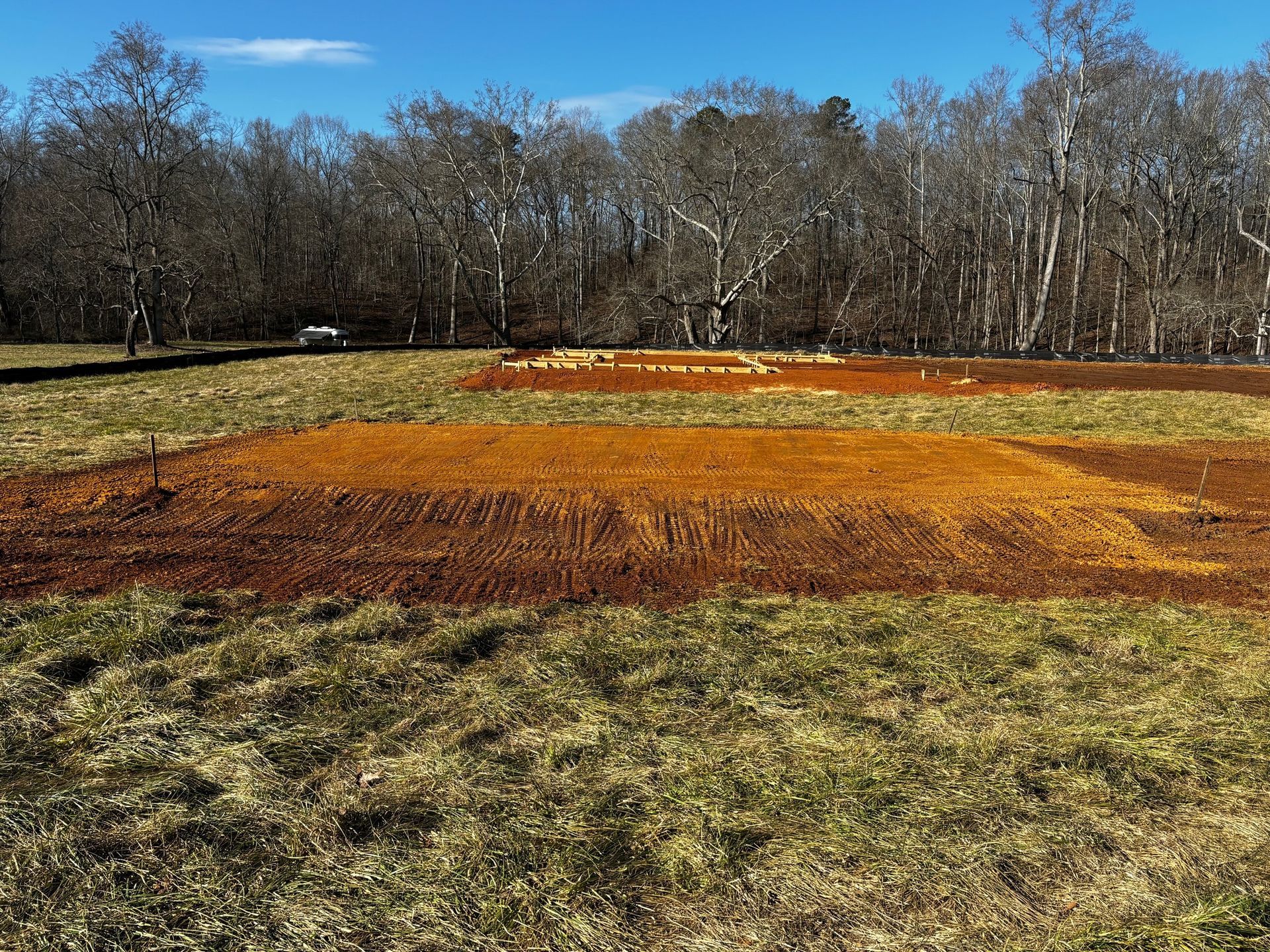 A baseball field with a lot of dirt in it and trees in the background.