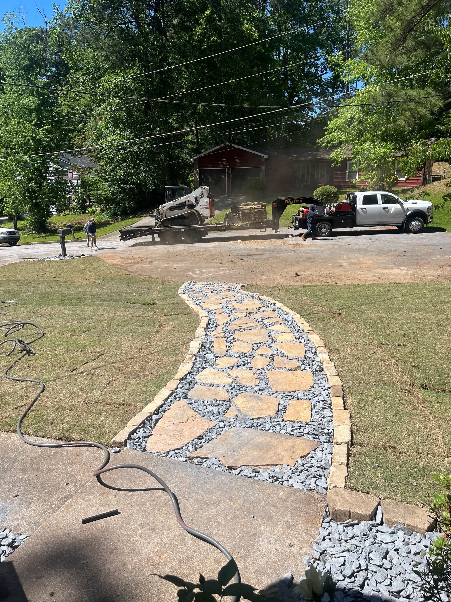 A white truck is parked in a driveway next to a stone walkway.