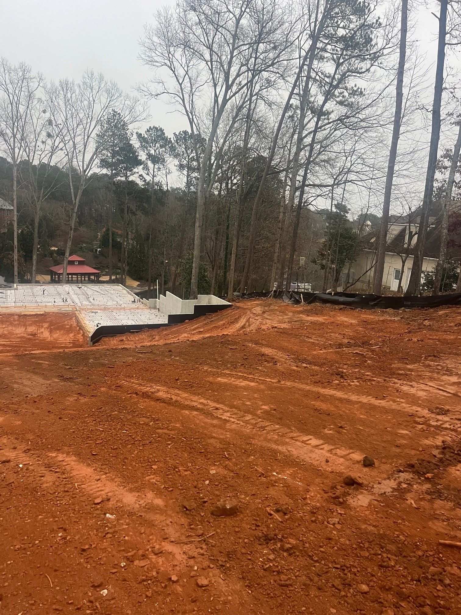 A dirt road with trees in the background and a house in the background.
