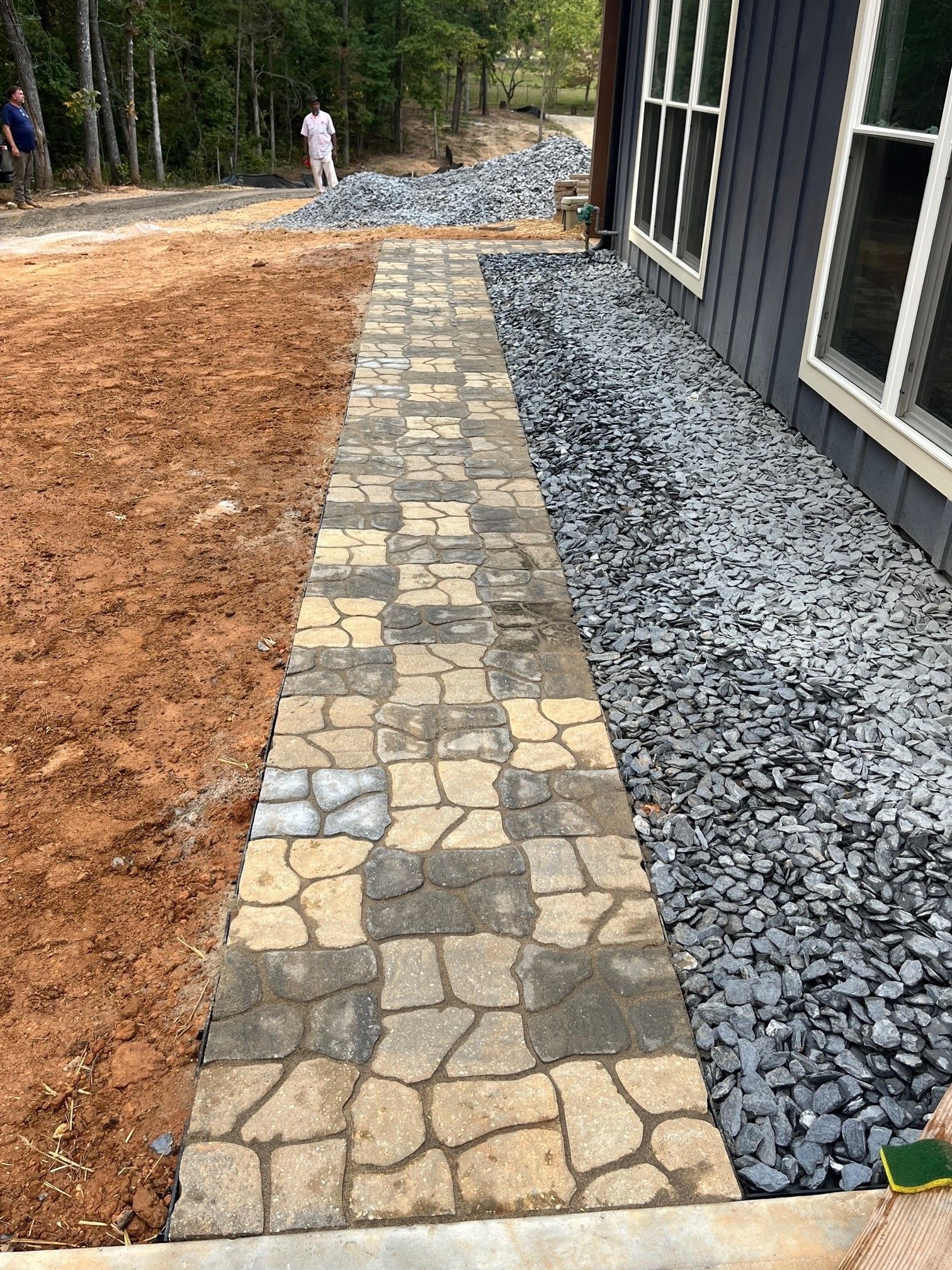 A stone walkway is being built in front of a house.