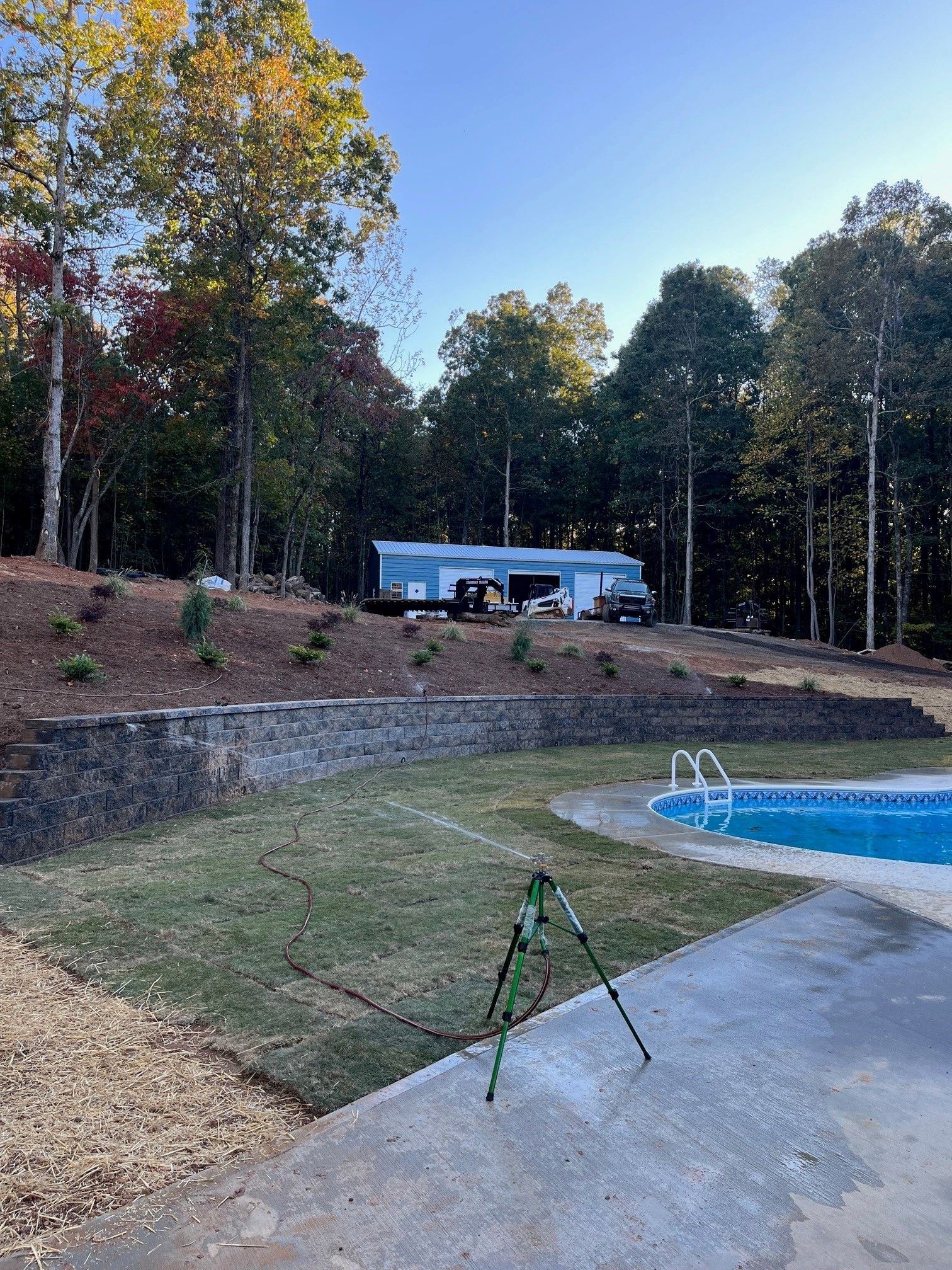 A tripod is sitting in front of a swimming pool in a backyard.
