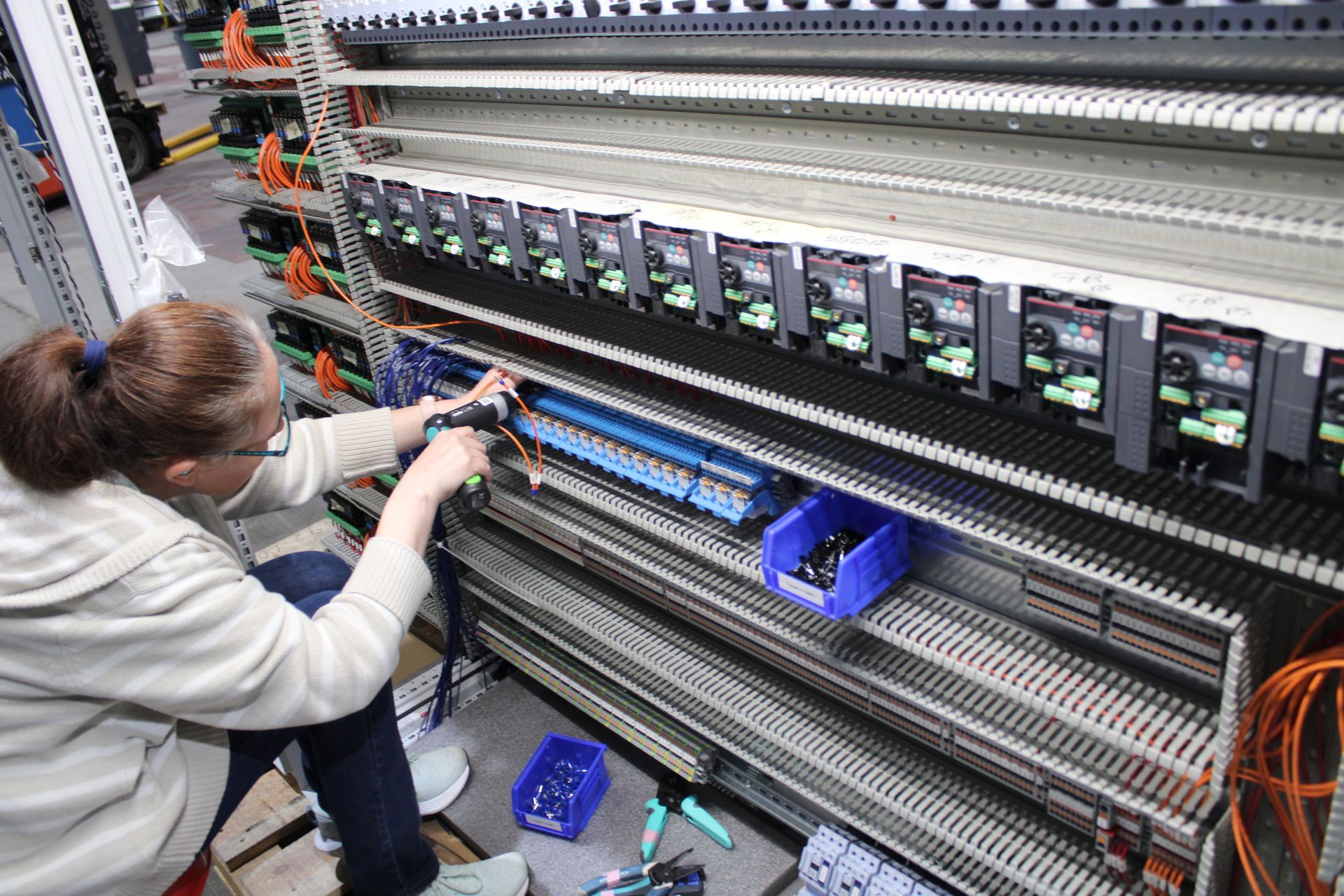 a woman is working on a electrical panel in a factory .