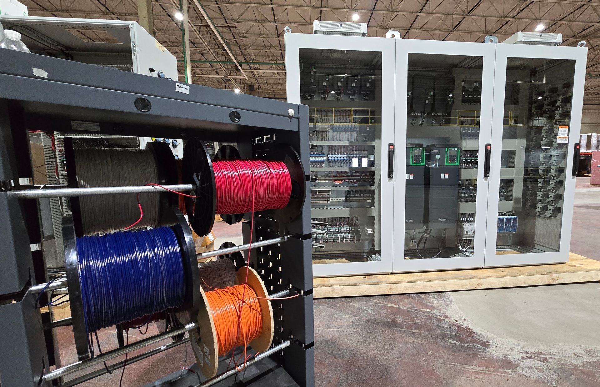 spools of wire on a cart positioned in front of a motor control center cabinet