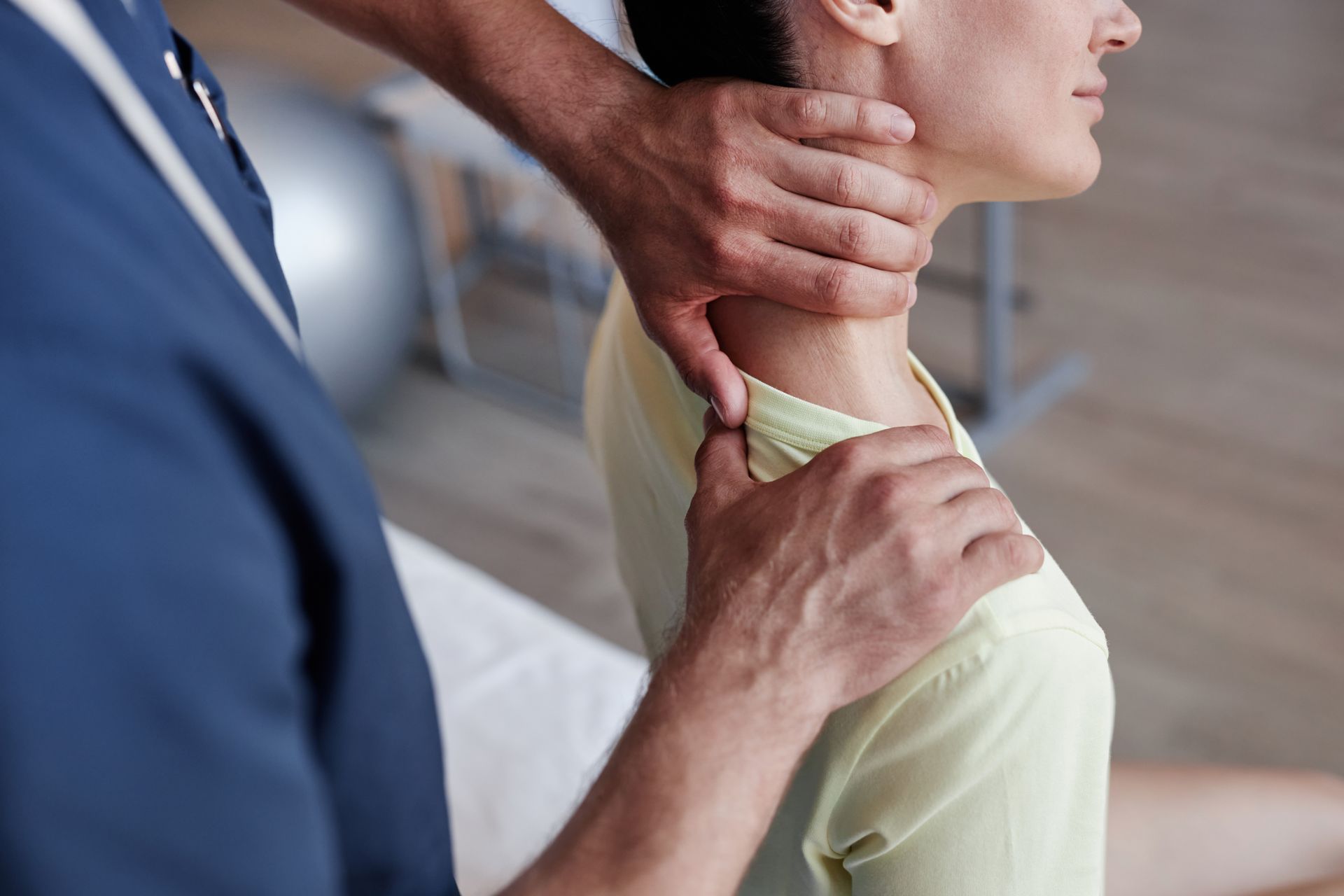 Close-up of a manual therapist massaging the neck of a young woman during therapy in a clinic.