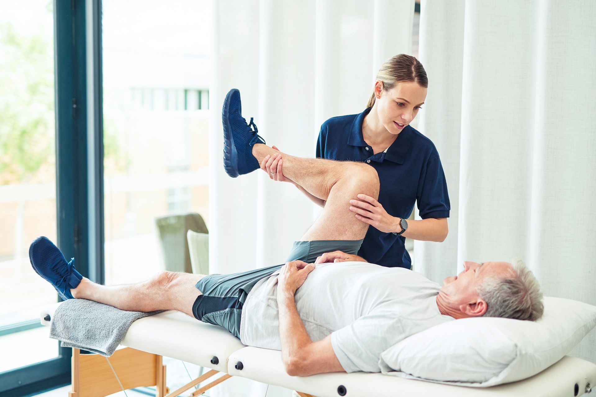 A physiotherapist is helping an injured elderly, through rehabilitation services.